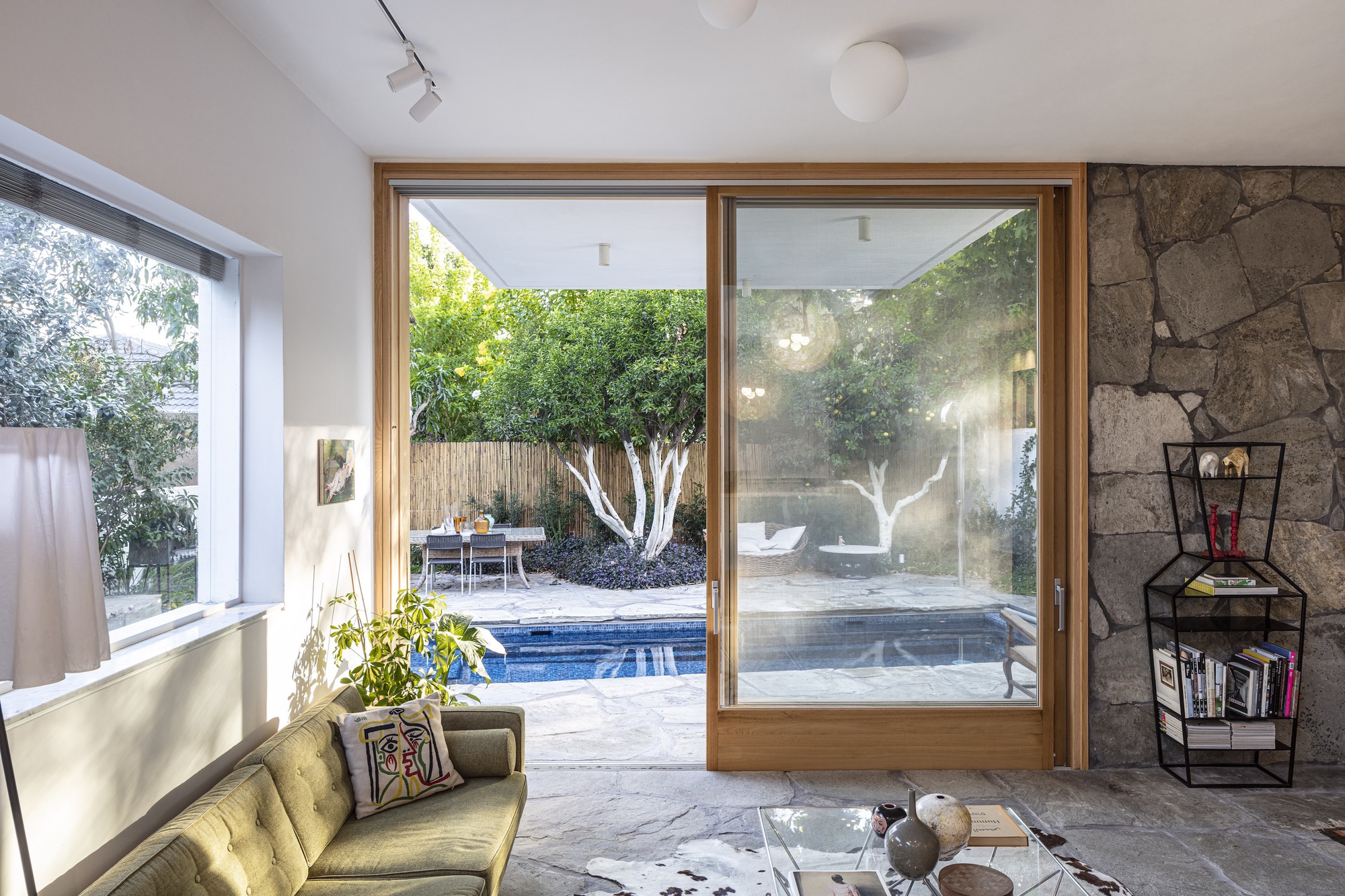 Timber sliding glass doors opening to pool terrace with stone feature wall and exposed ceiling pendant