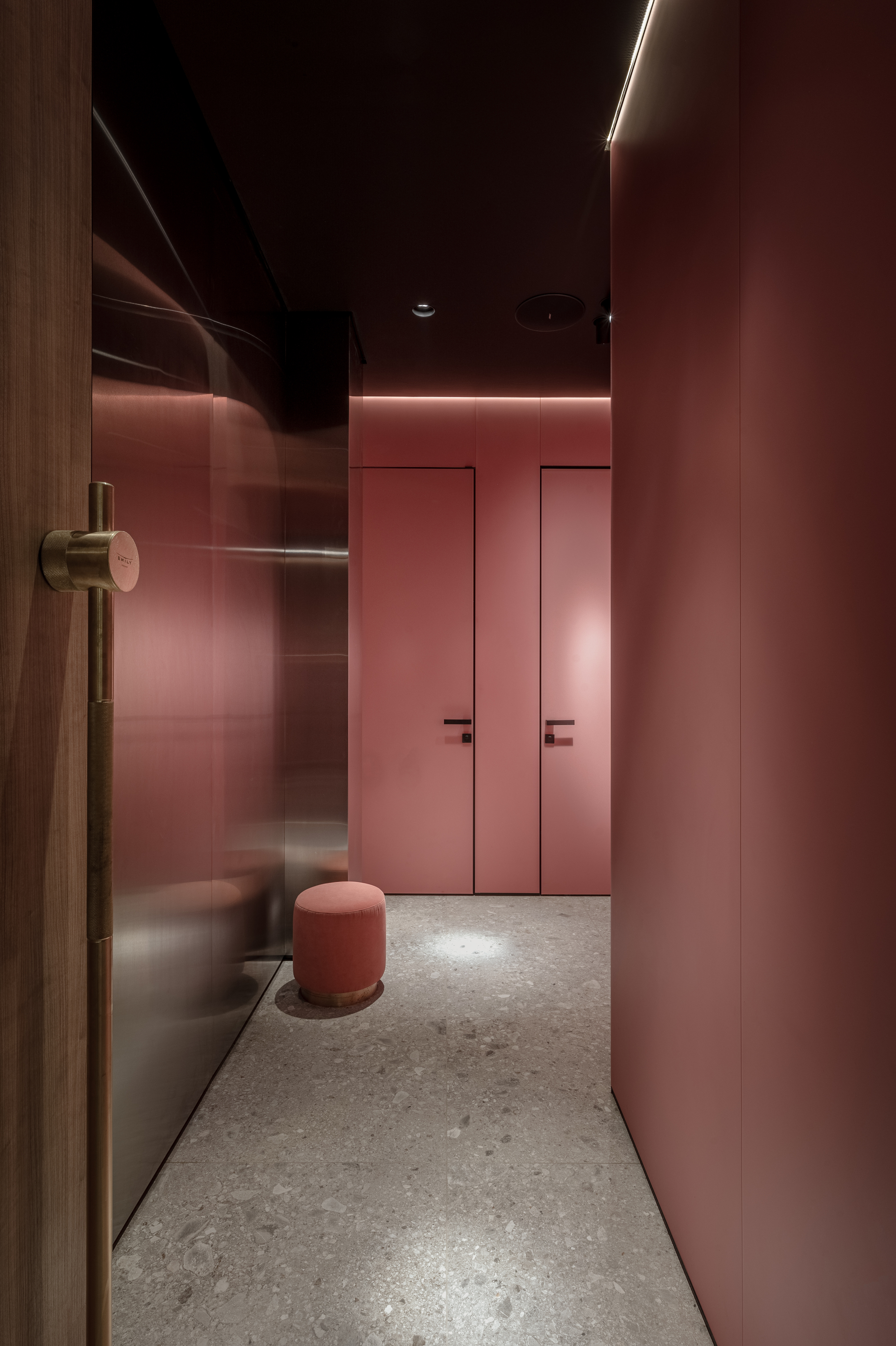 Narrow corridor with pink wall panels and concealed LED lighting at the ceiling line