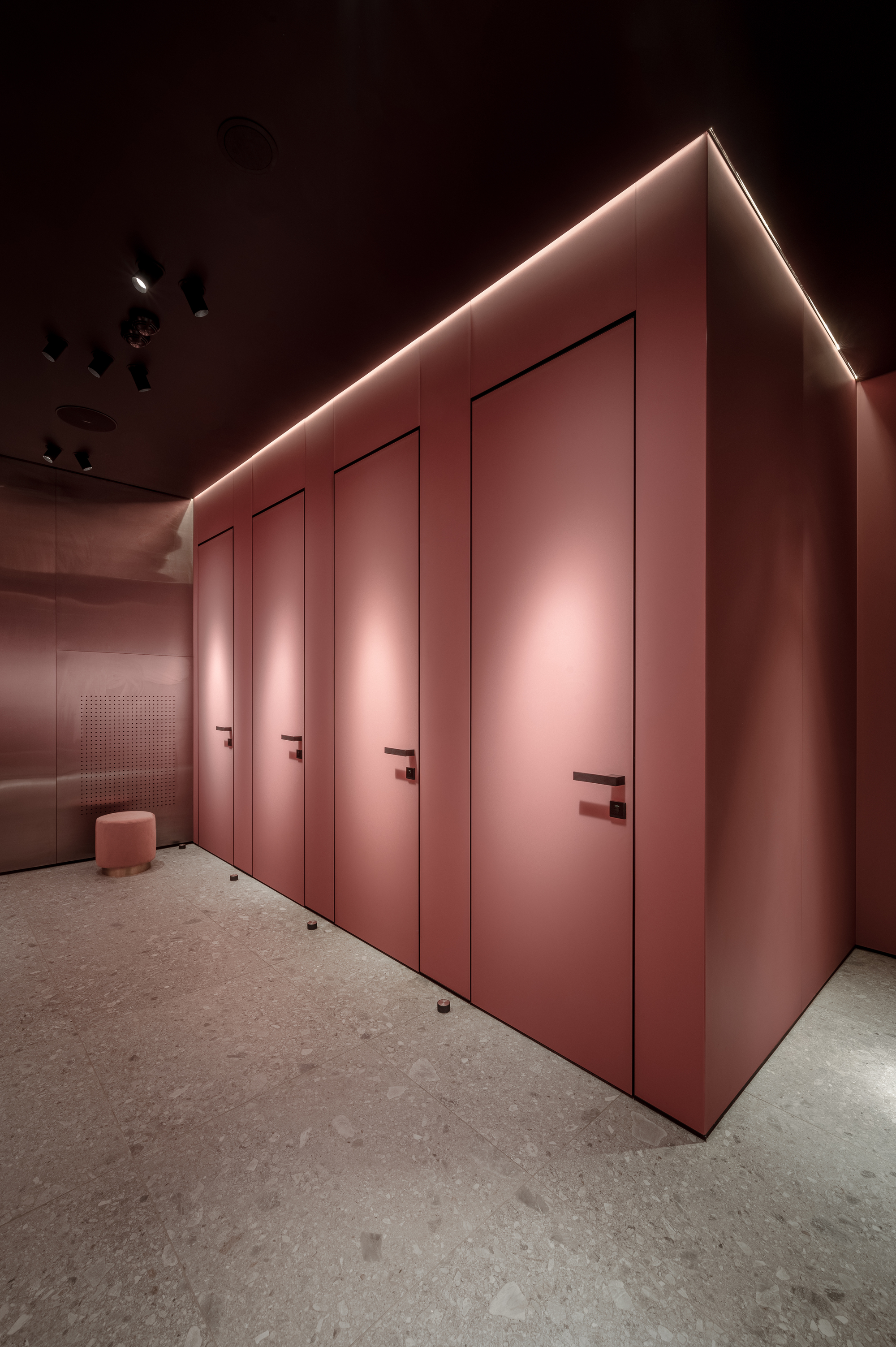 Row of four pink flush doors with concealed LED perimeter lighting and terrazzo flooring