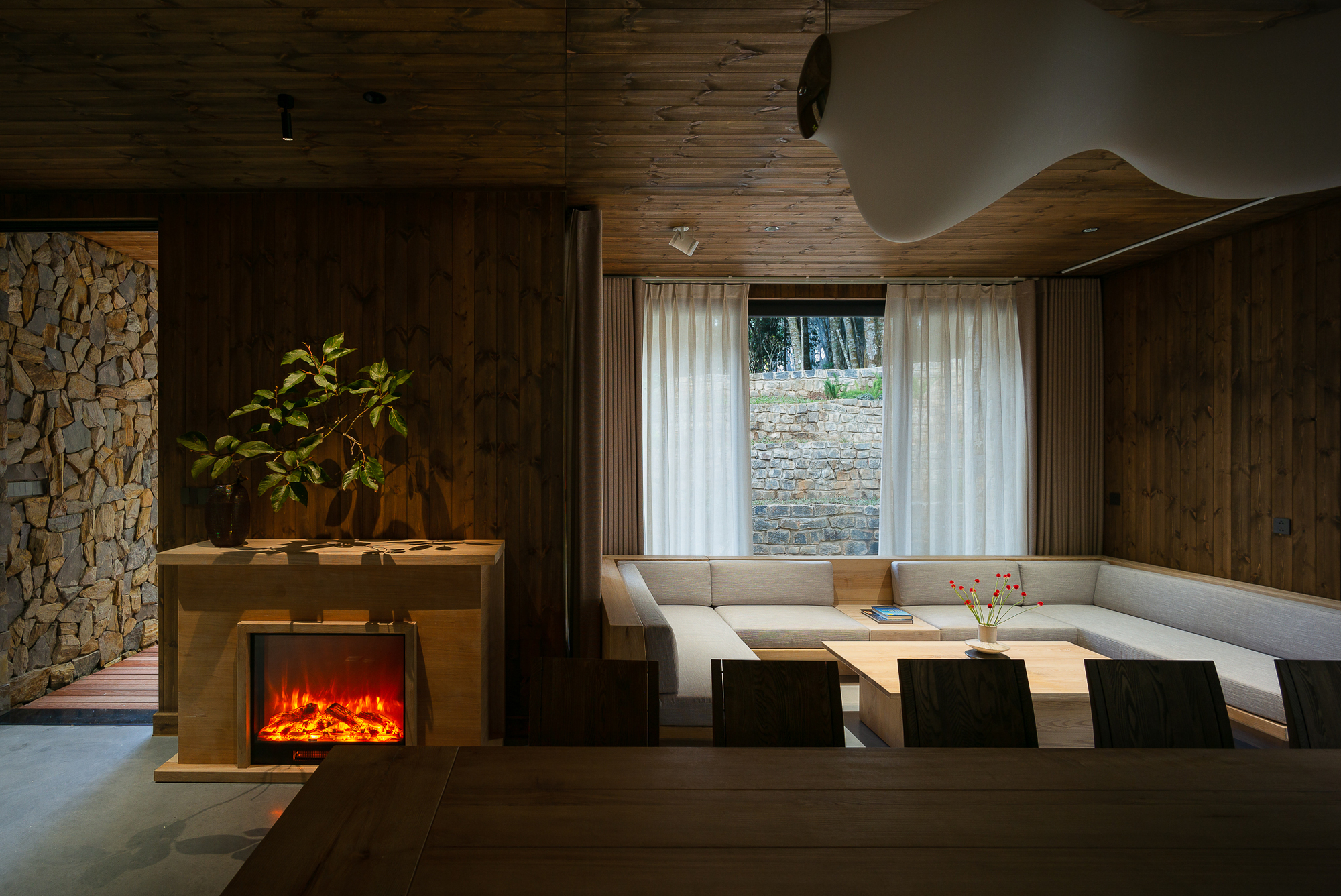 Living area with built-in seating nook, electric fireplace, and wood-paneled ceiling