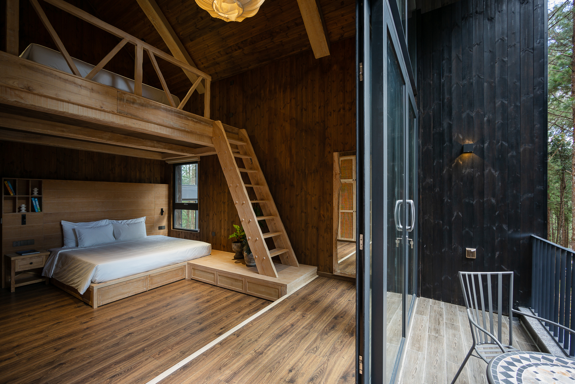 Bedroom with timber loft and open glass doors leading to a corrugated metal-clad balcony