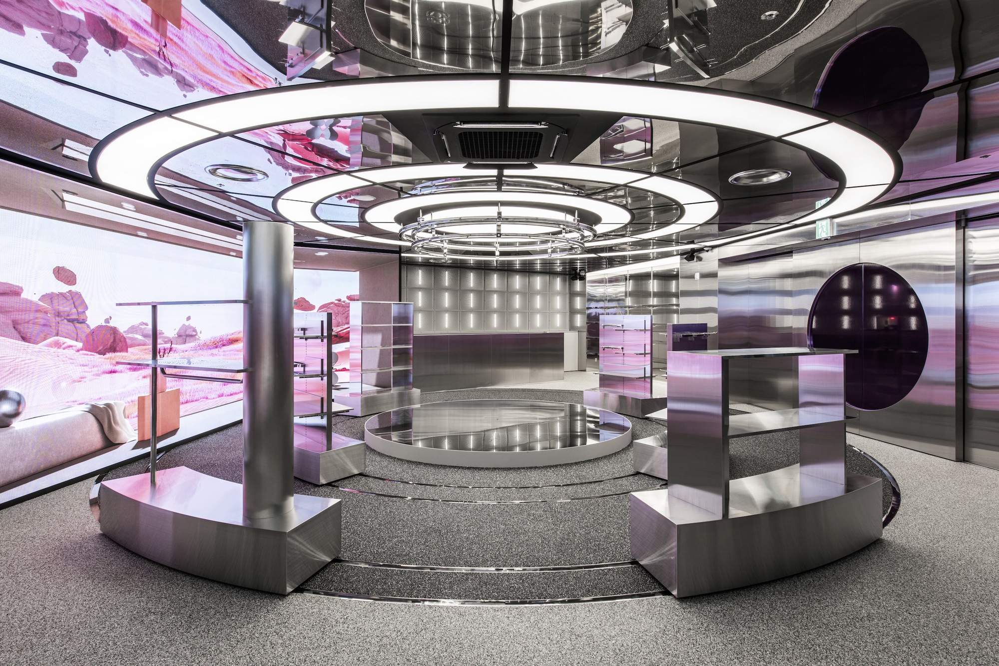 Central stepped platform with steel columns and ring lighting beneath pink projected landscape on wraparound screens