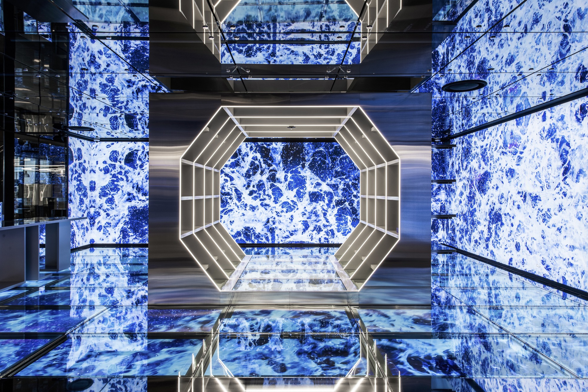 Upward view through octagonal atrium with illuminated frame and blue patterned wall panels