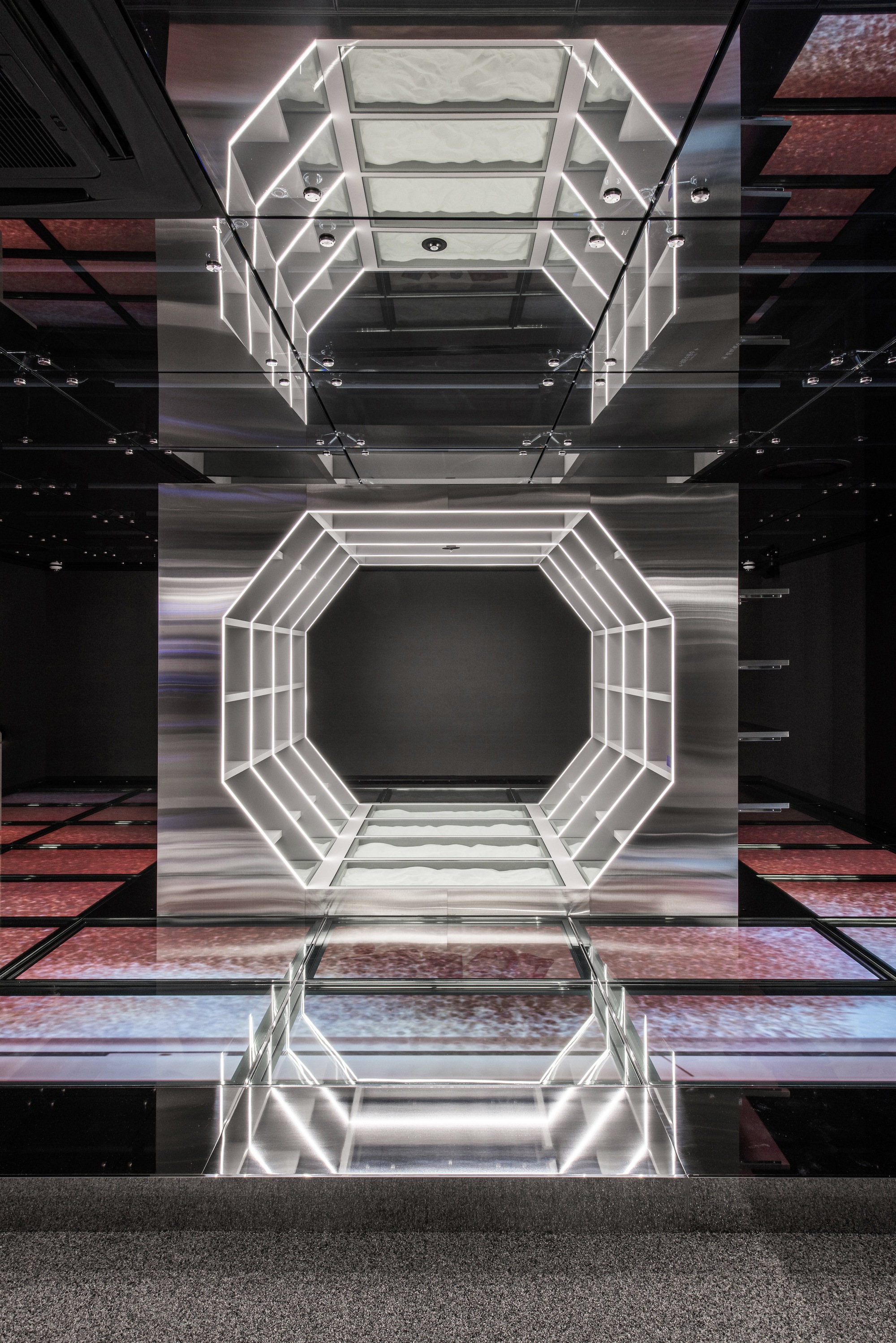 Vertical atrium view showing octagonal light frame reflected in polished floor below