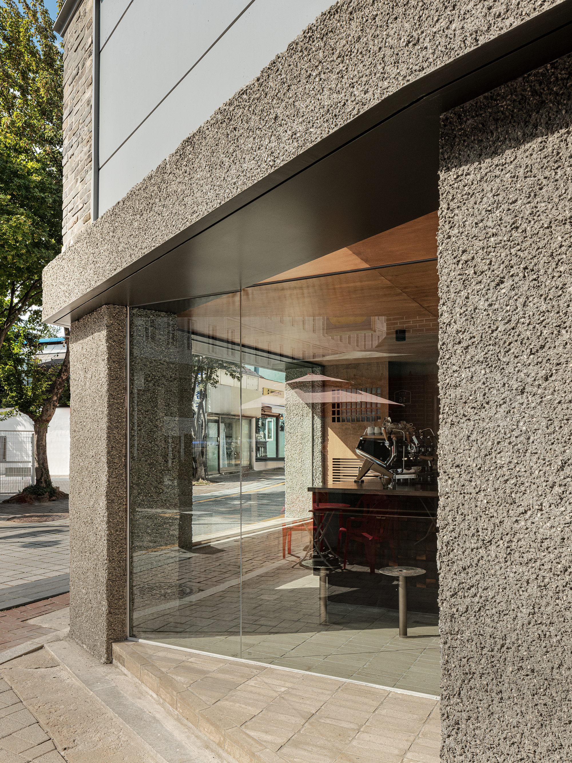 Glazed corner entrance framed by textured concrete columns in afternoon light