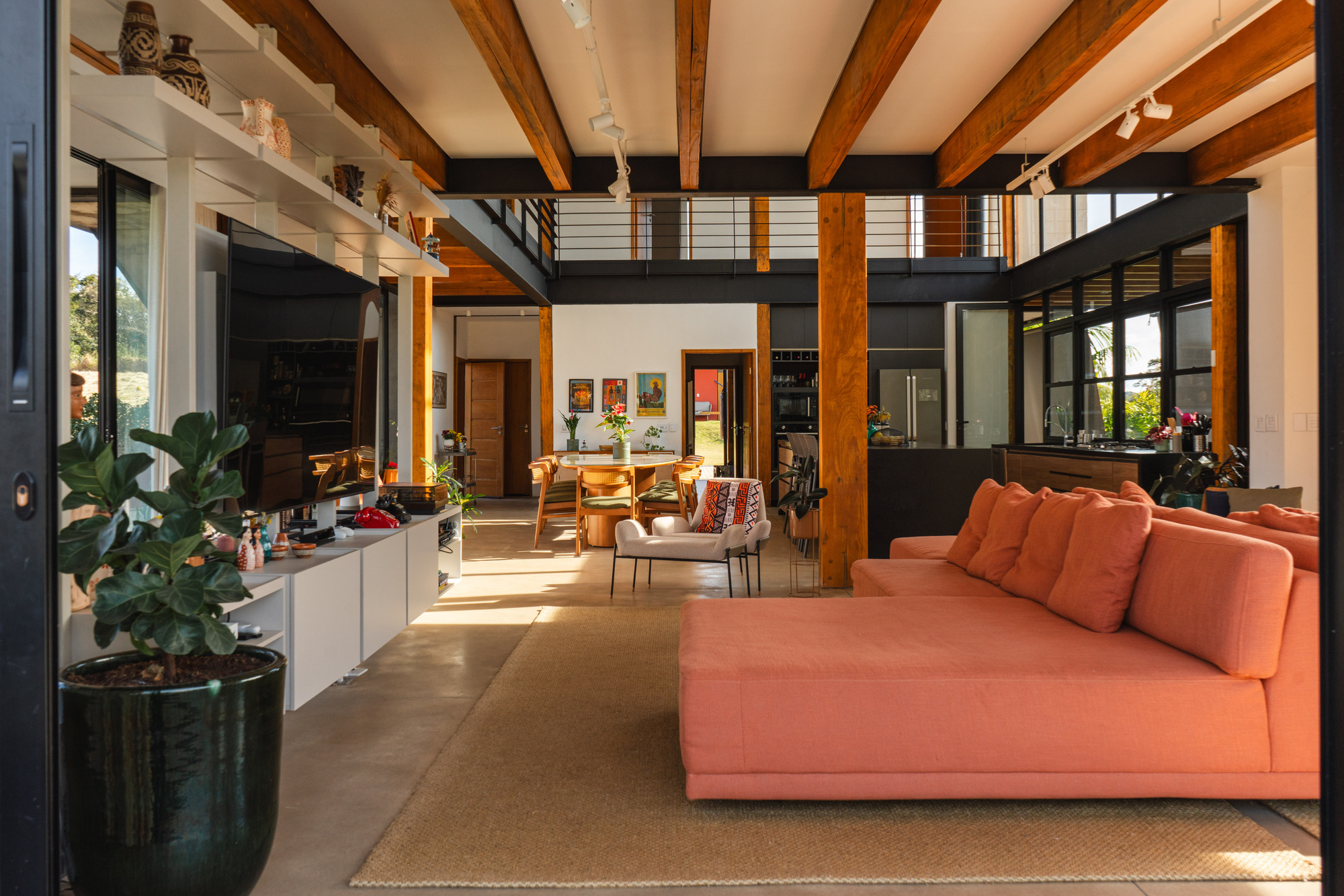 Interior showing double-height space with timber columns and black steel mezzanine in afternoon sun