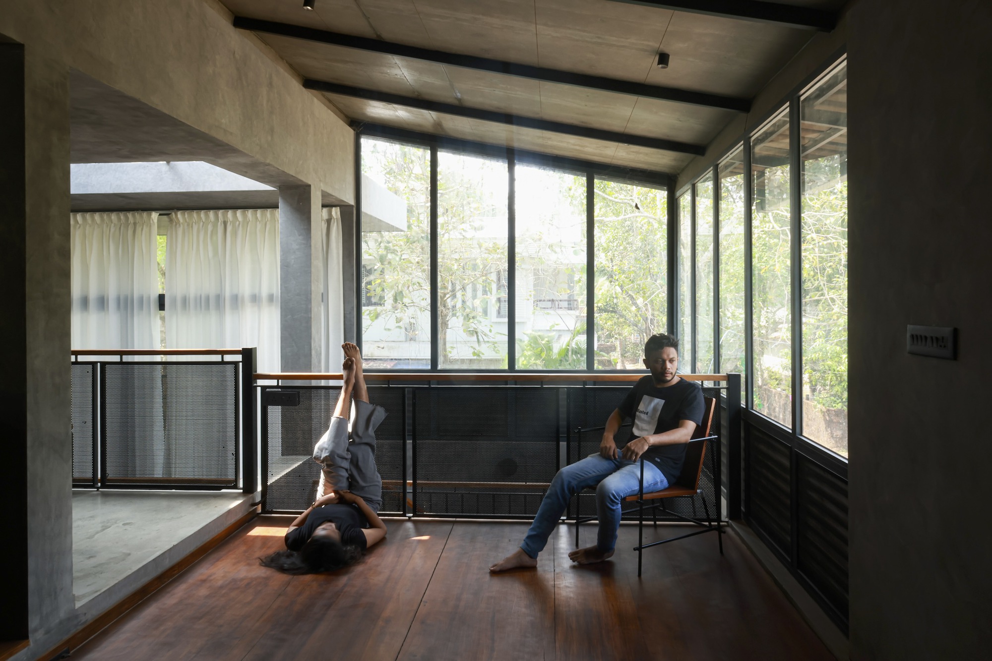 Timber floor study room with concrete ceiling beams and two occupants by glazed wall