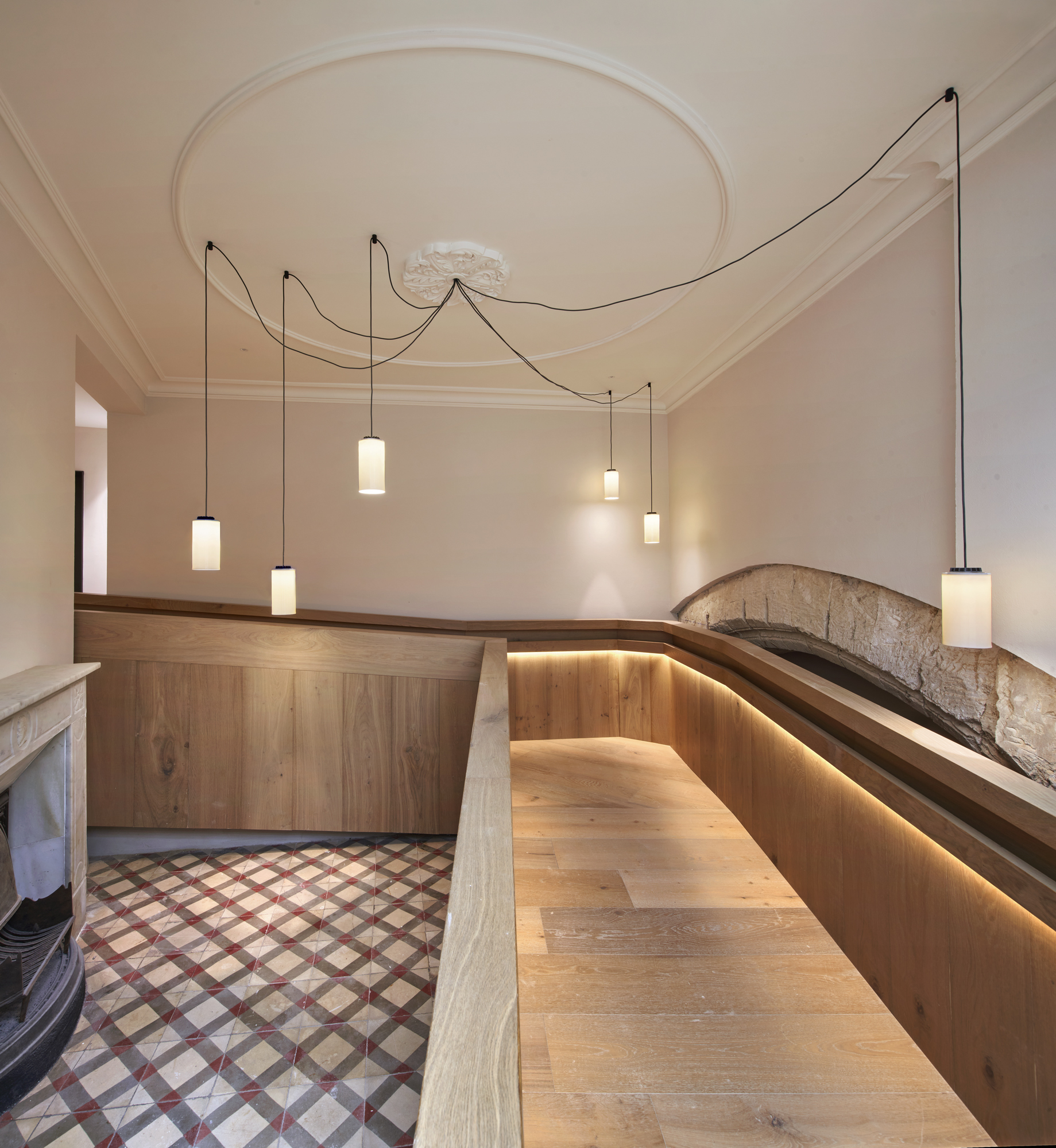 Curved timber bench with integrated lighting below pendant fixtures and a circular ceiling medallion
