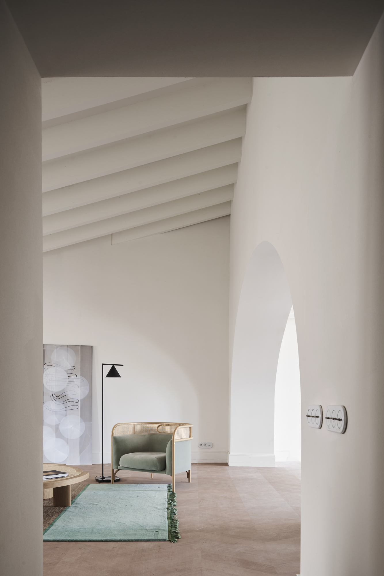 View through arched opening into a double-height space with ribbed vaulted ceiling and pale plaster walls
