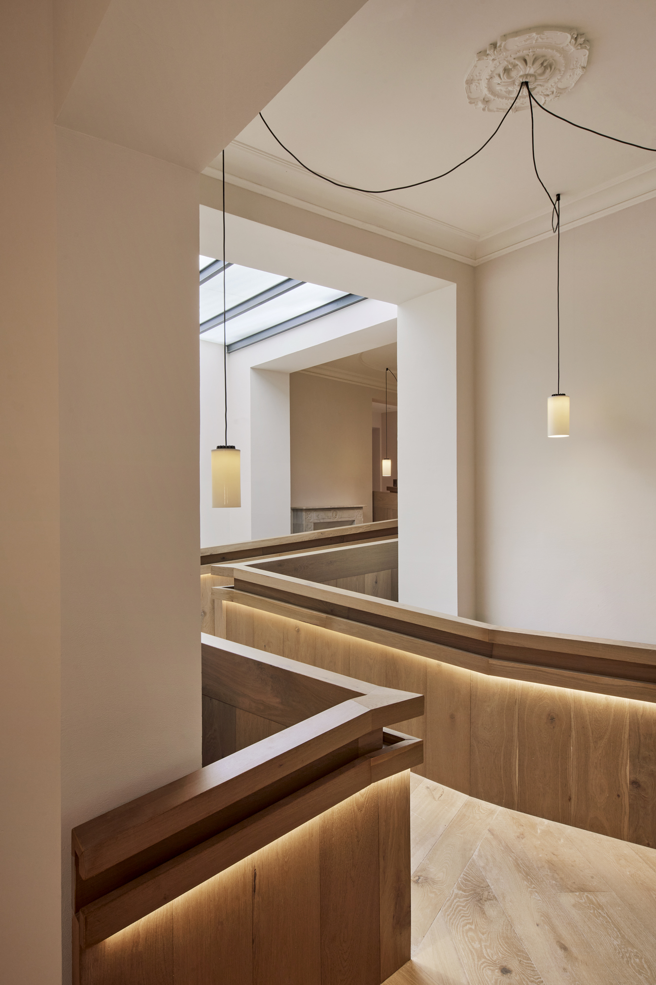 View through doorway to timber pews with integrated strip lighting and pendant fixtures below ceiling rosette