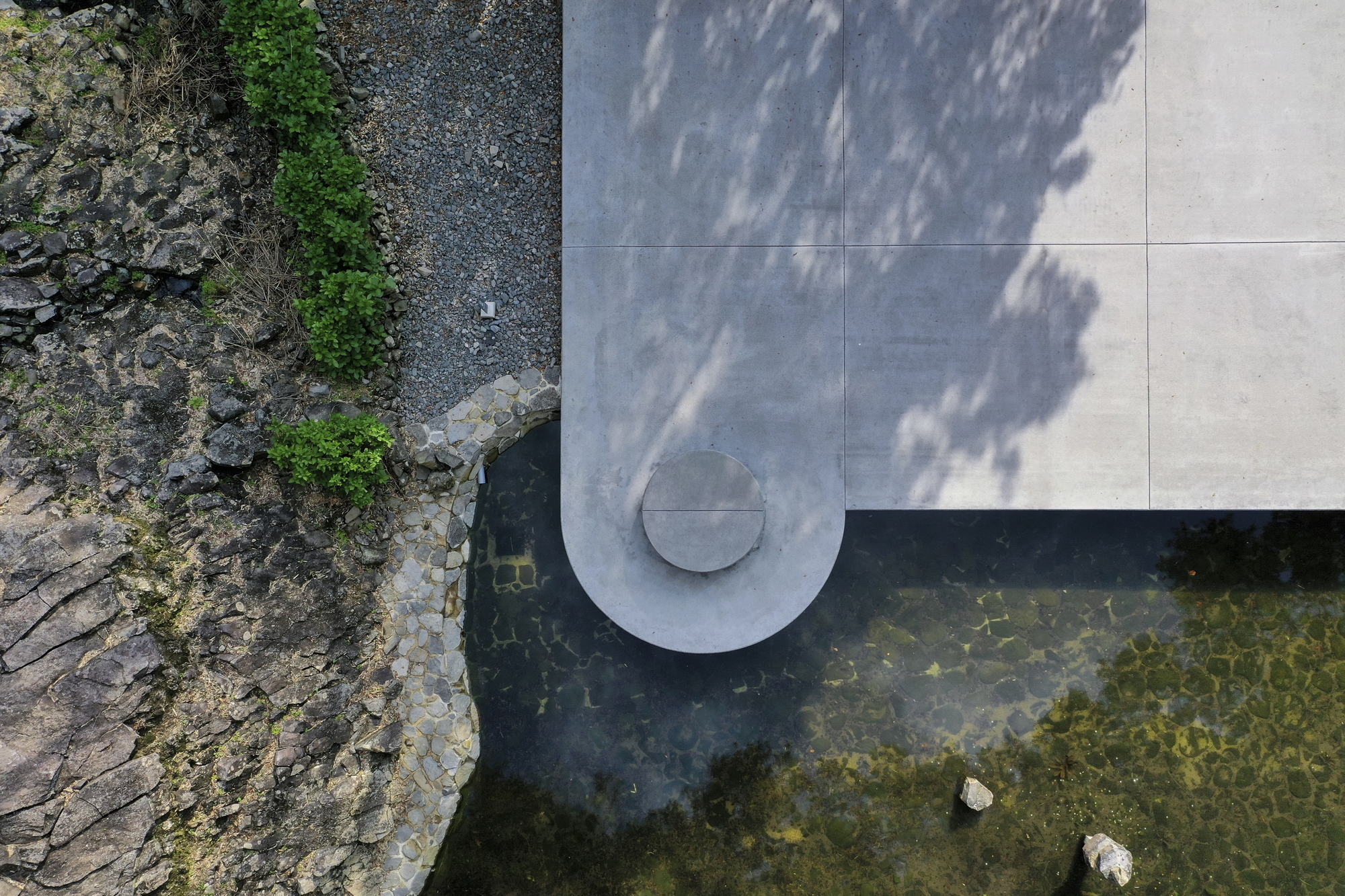 Overhead view of the concrete cantilever with circular vent extending over dark quarry water