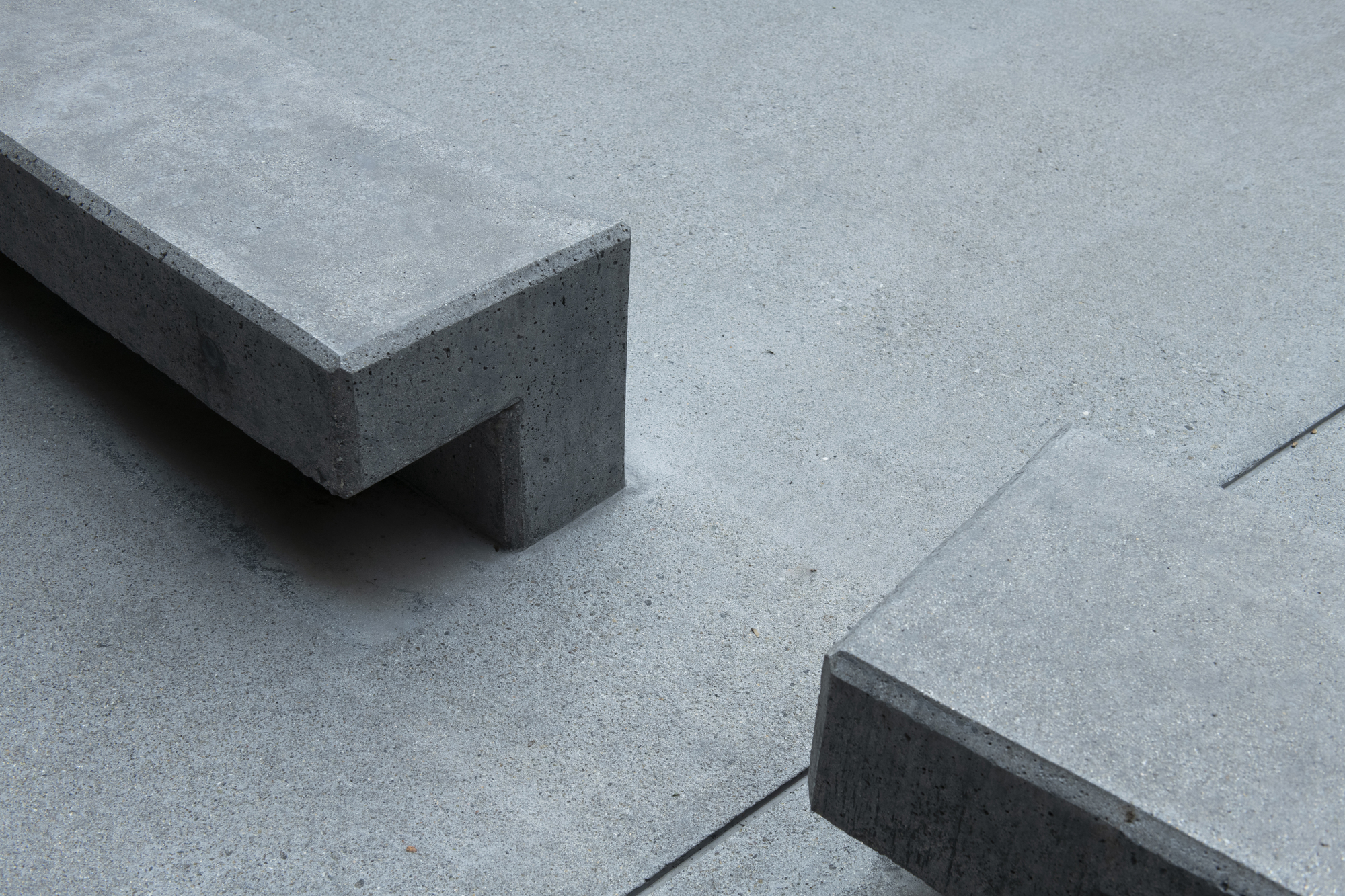 Detail of concrete bench corner casting shadow on poured concrete plaza surface