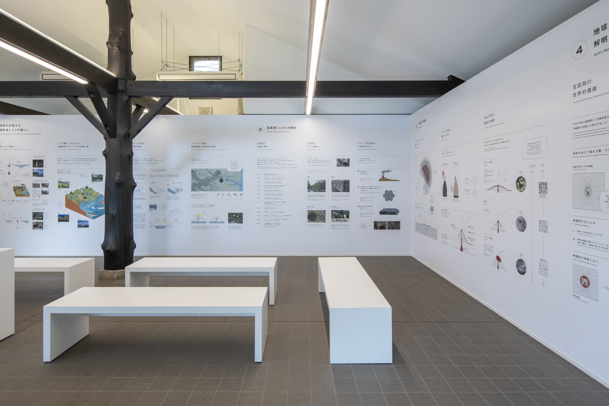 Gallery interior with white display panels on walls, white benches, and exposed timber columns