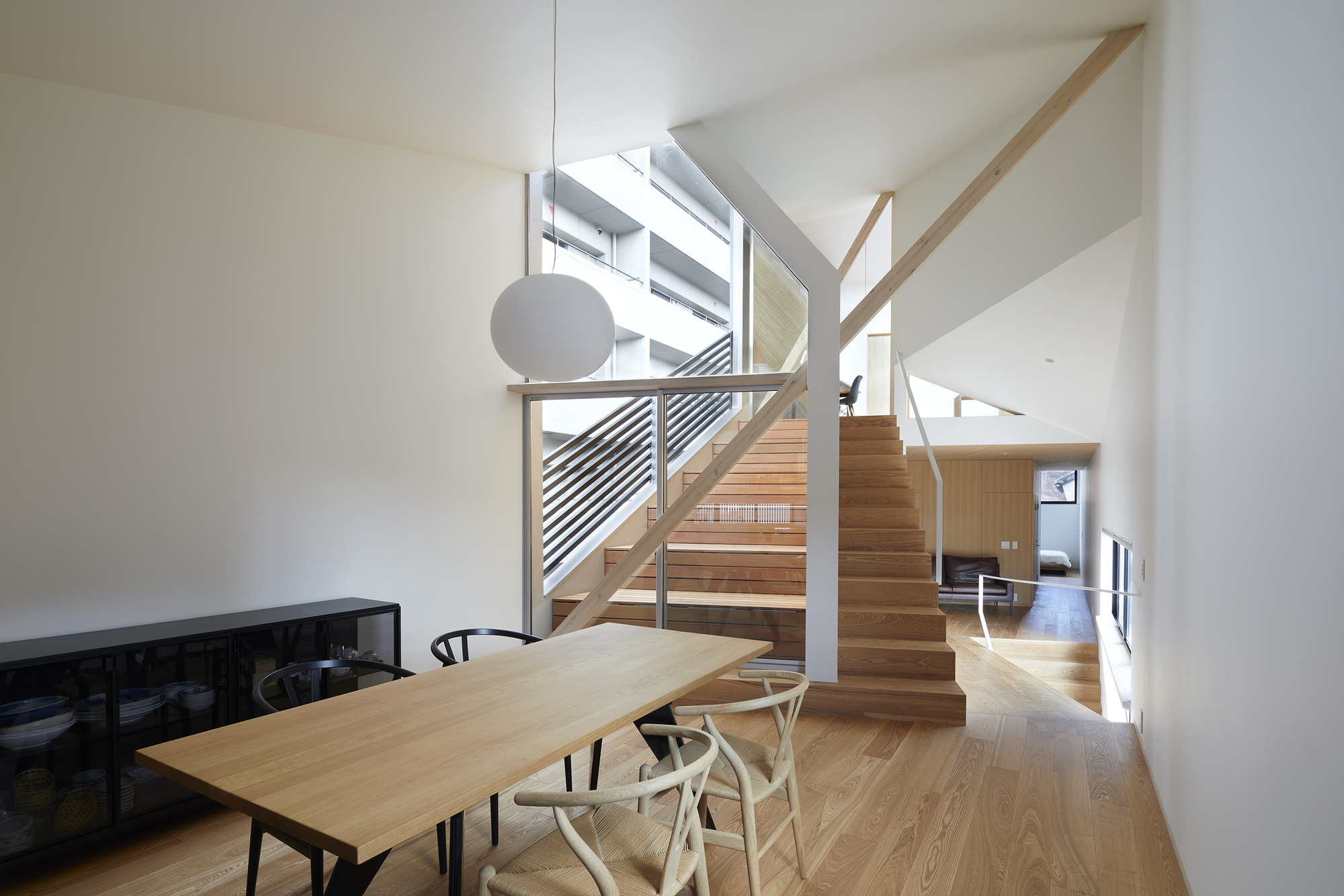 Open staircase with timber treads and diagonal metal railing connecting dining area to upper levels
