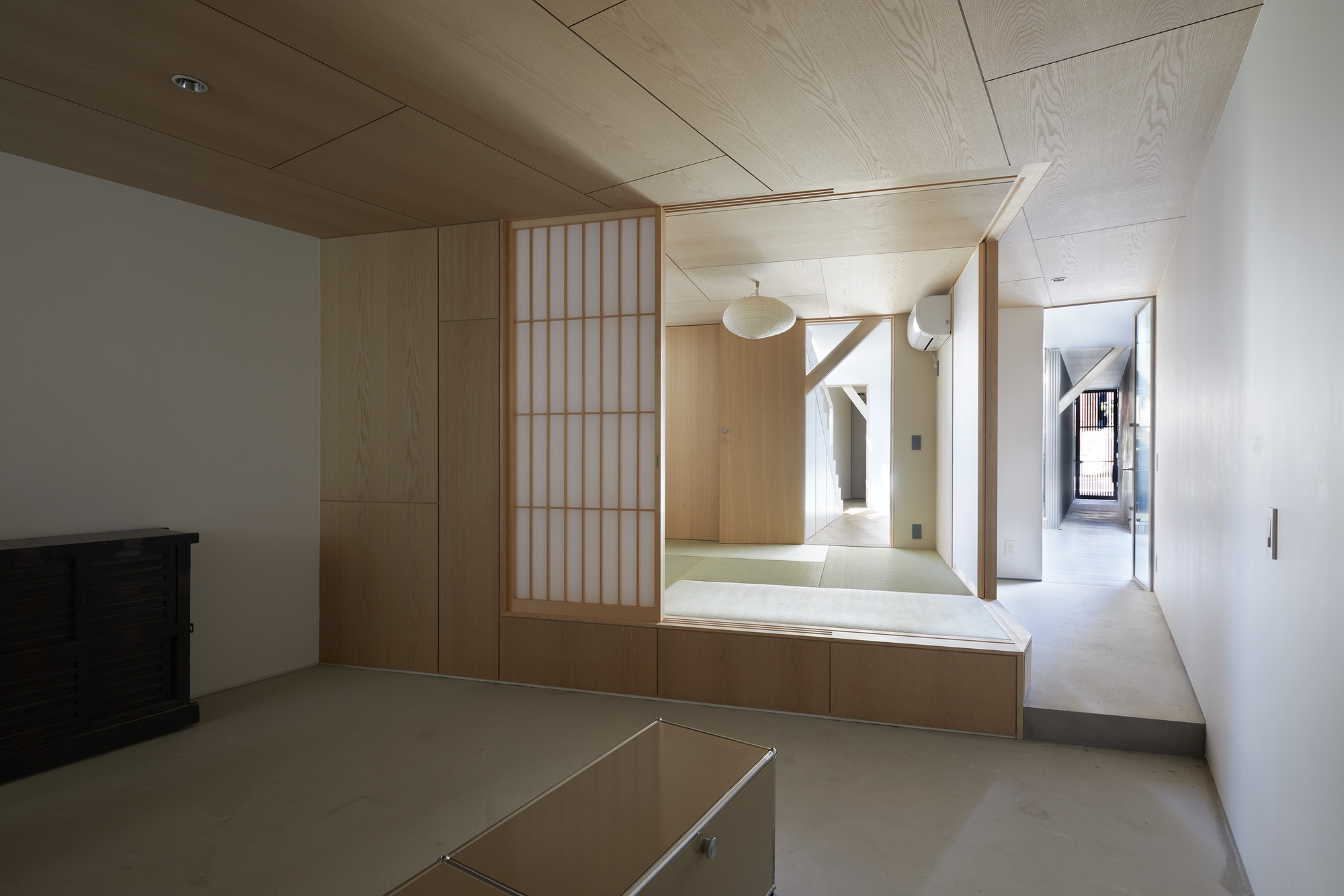 Interior room with plywood ceiling and raised tatami platform behind translucent shoji screen
