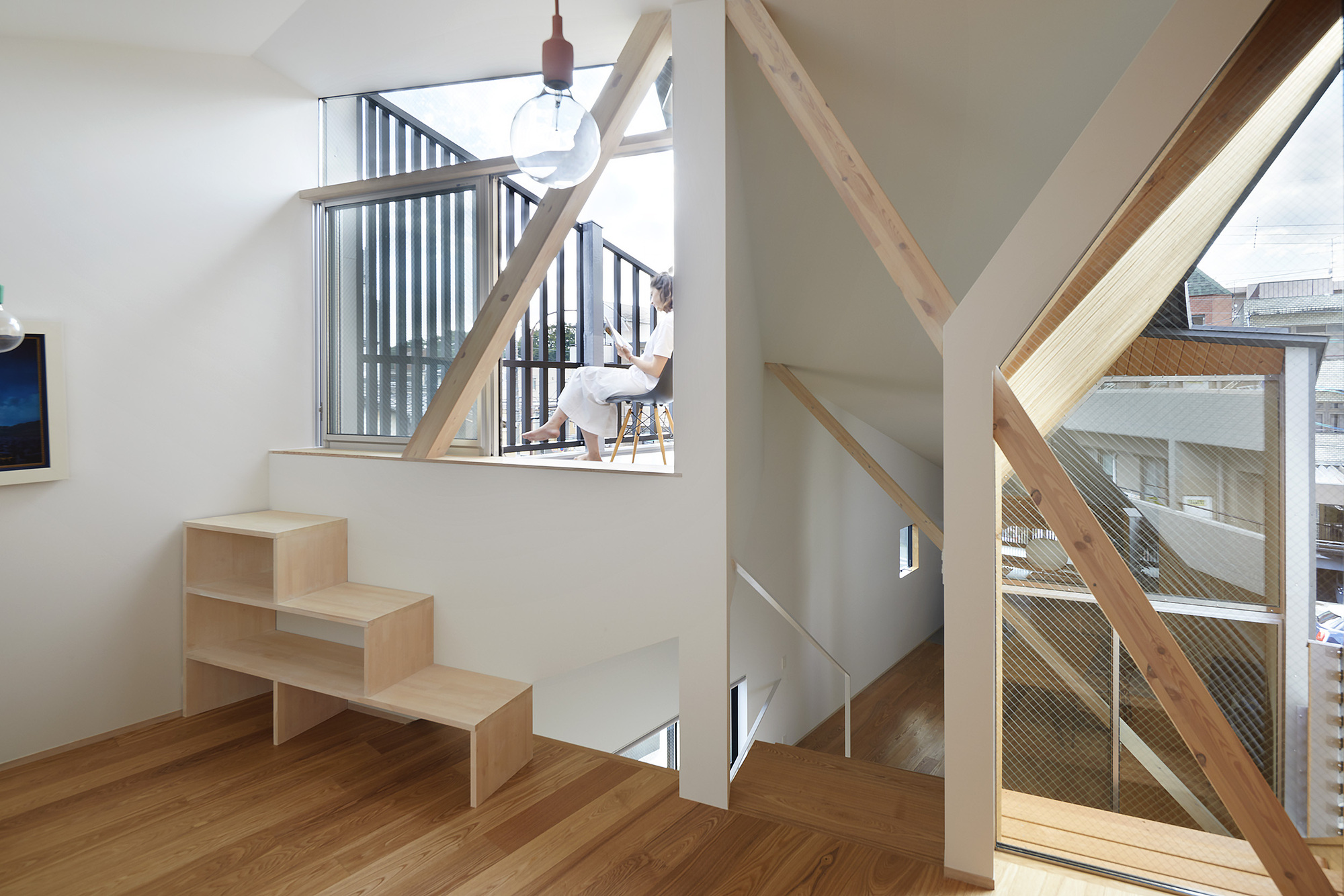 Upper level corridor with plywood shelving unit and diagonal timber bracing framing wire mesh balustrades