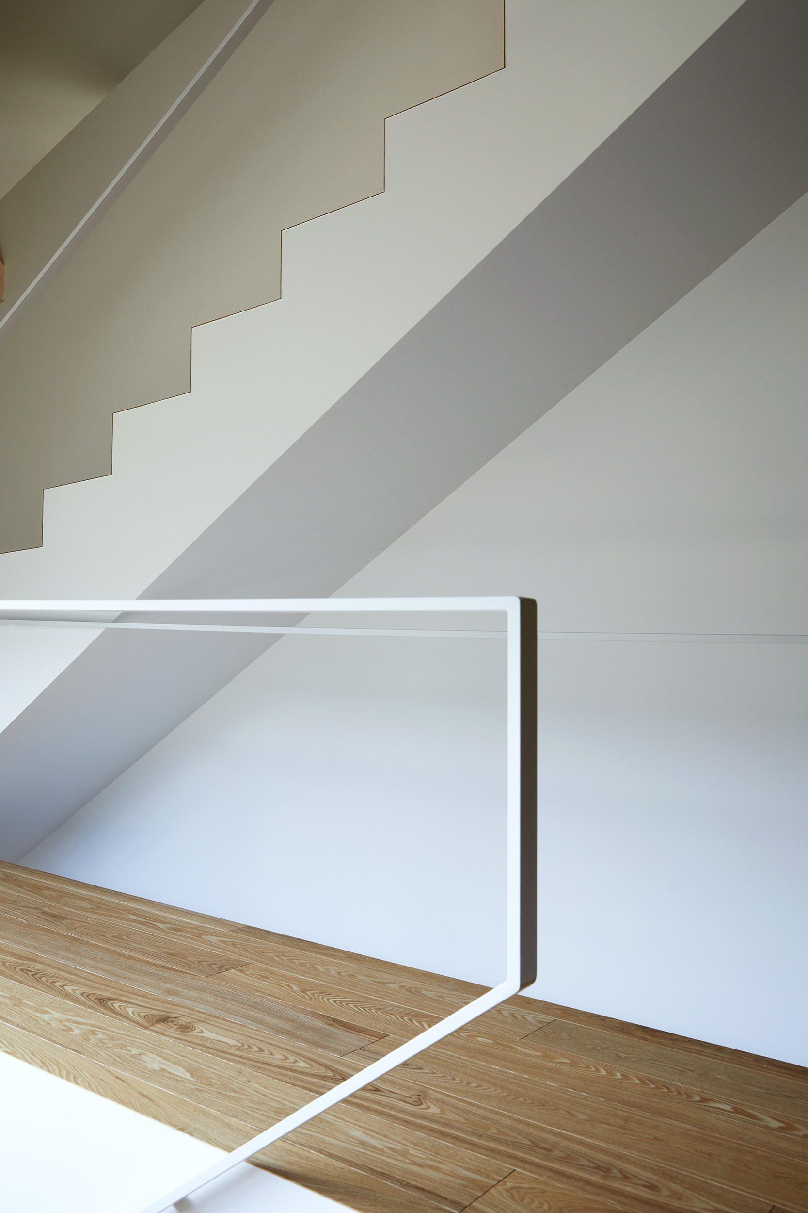 White staircase wall with shadow patterns cast by the railing and natural light