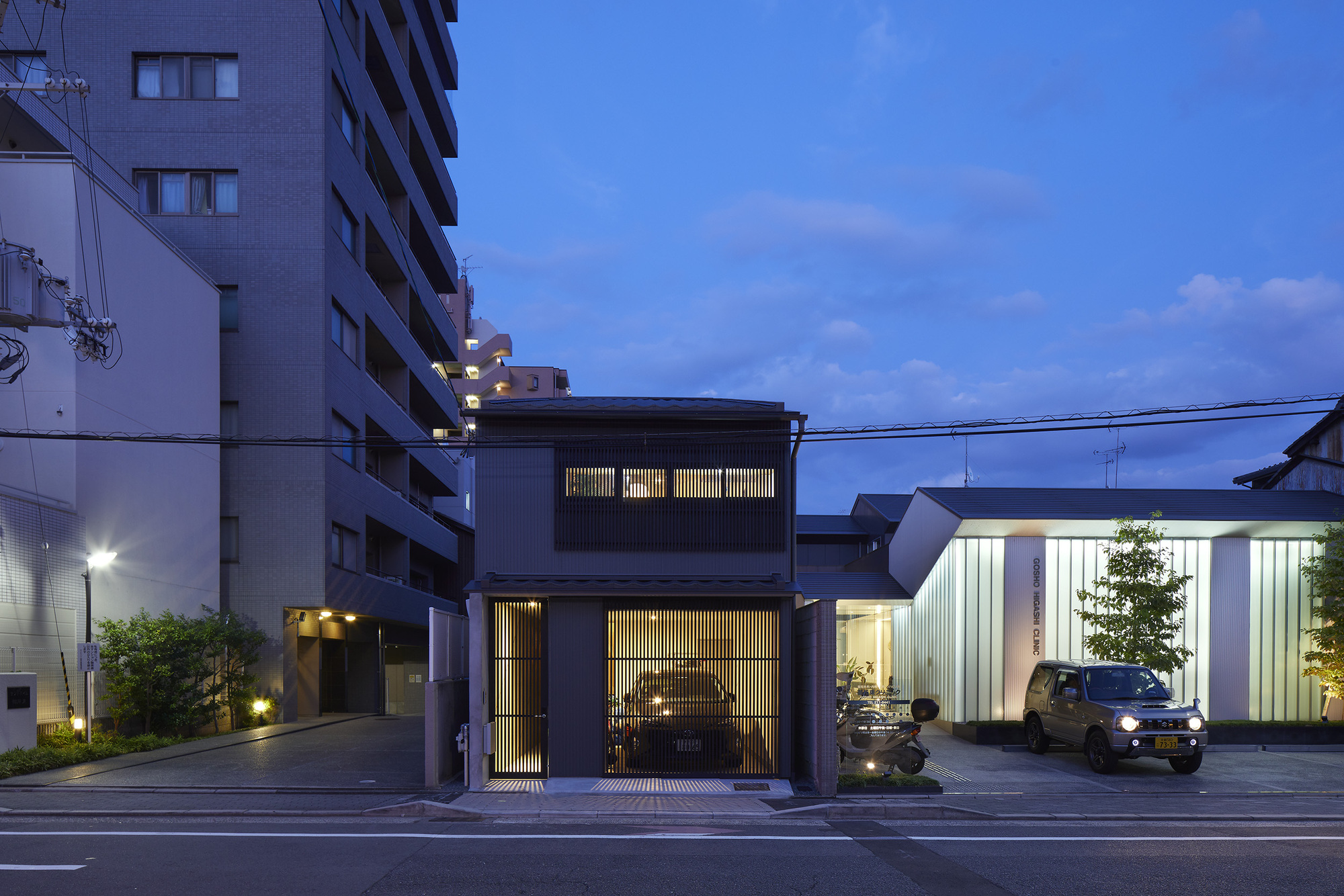 Street view of the two-storey facade with vertical timber screens at dusk