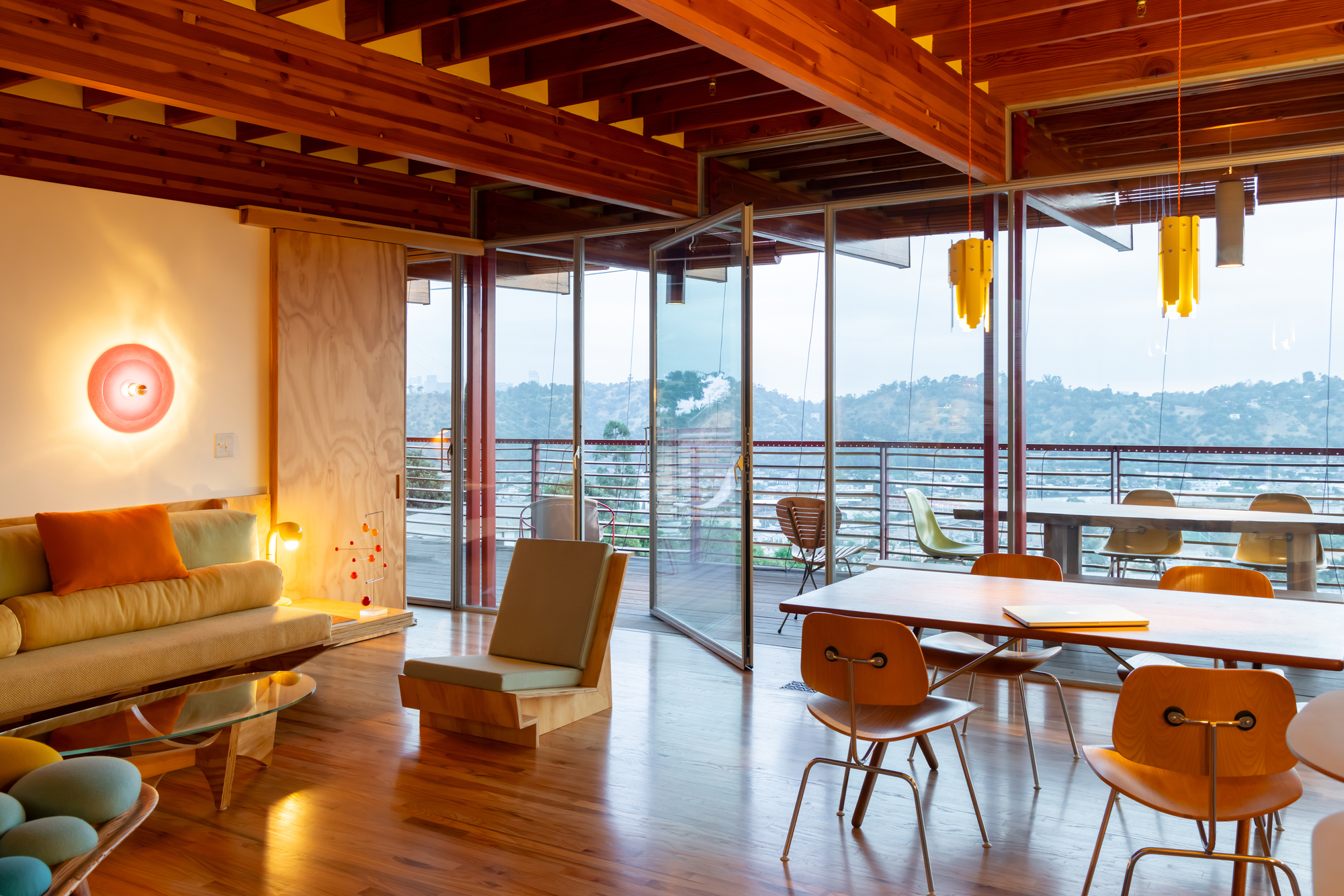 Dining area with exposed timber beams and sliding glass doors opening onto a deck with mountain views