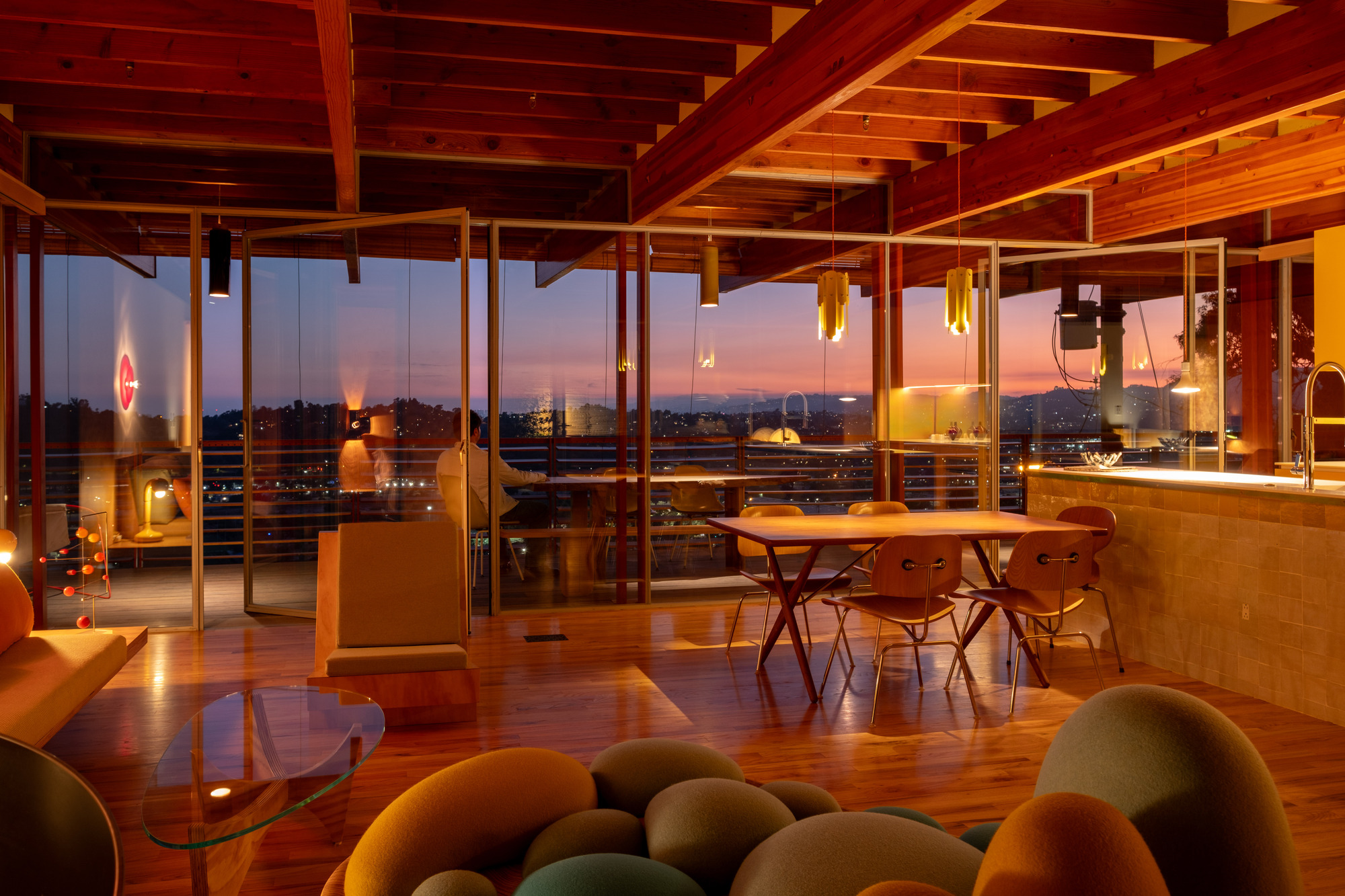Interior at dusk showing timber ceiling structure and full-height glazing with city lights beyond