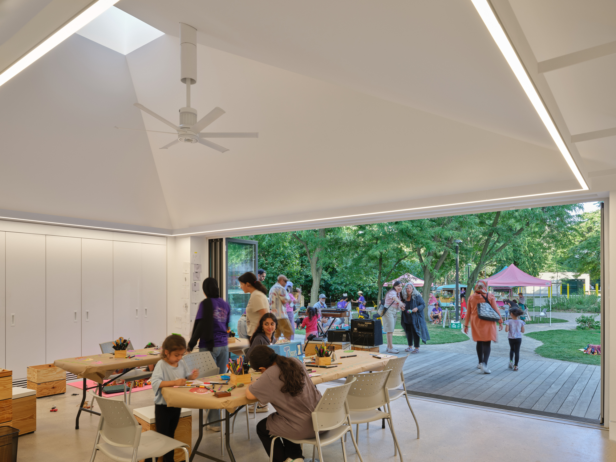 Interior view with vaulted ceiling and skylight opening to a wooden deck and park gathering beyond