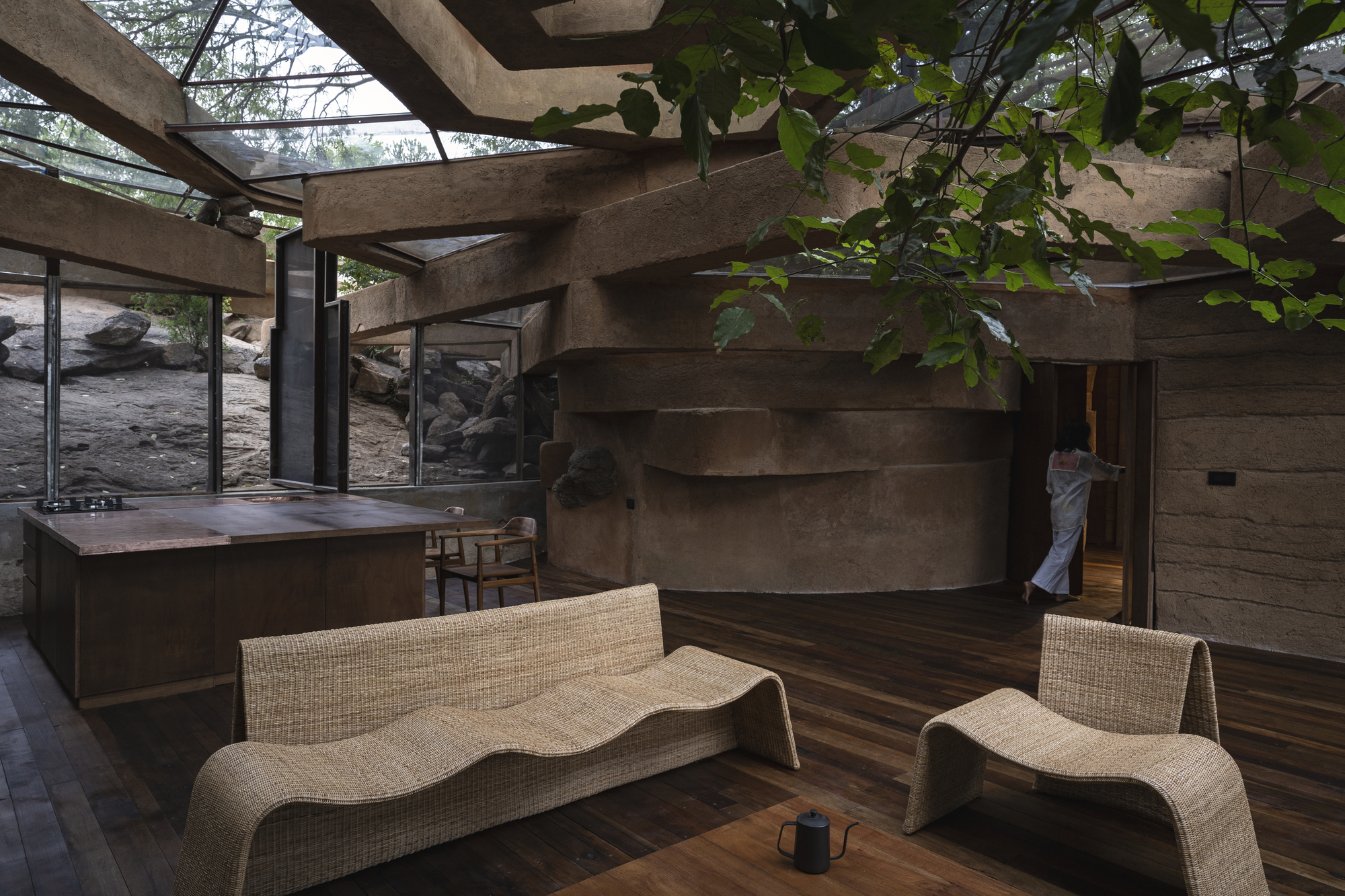 Stepped concrete wall wrapping the interior with exposed roof beams and partial glass ceiling