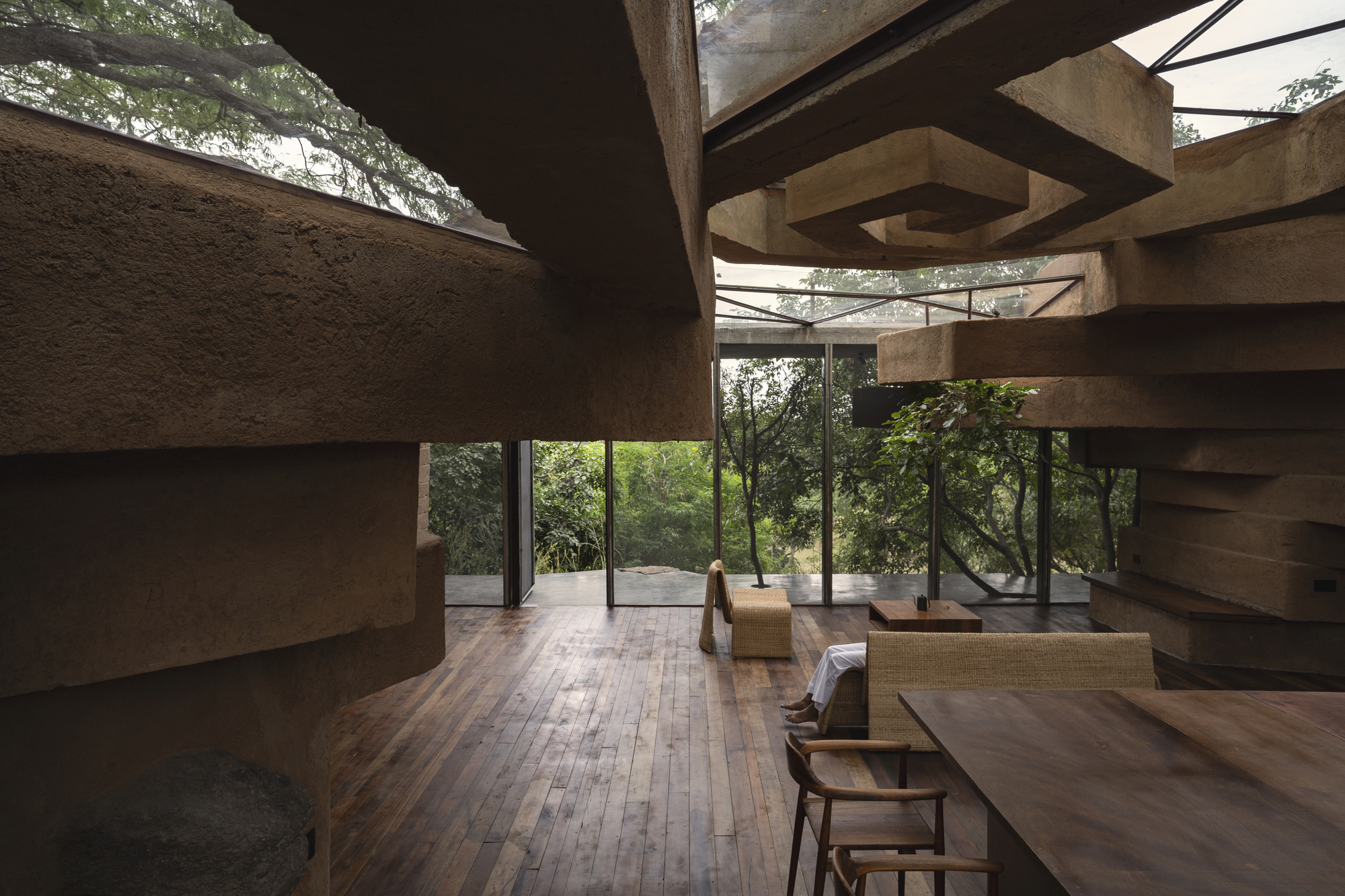 Double-height living area framed by horizontal concrete beams and full-height glazed walls
