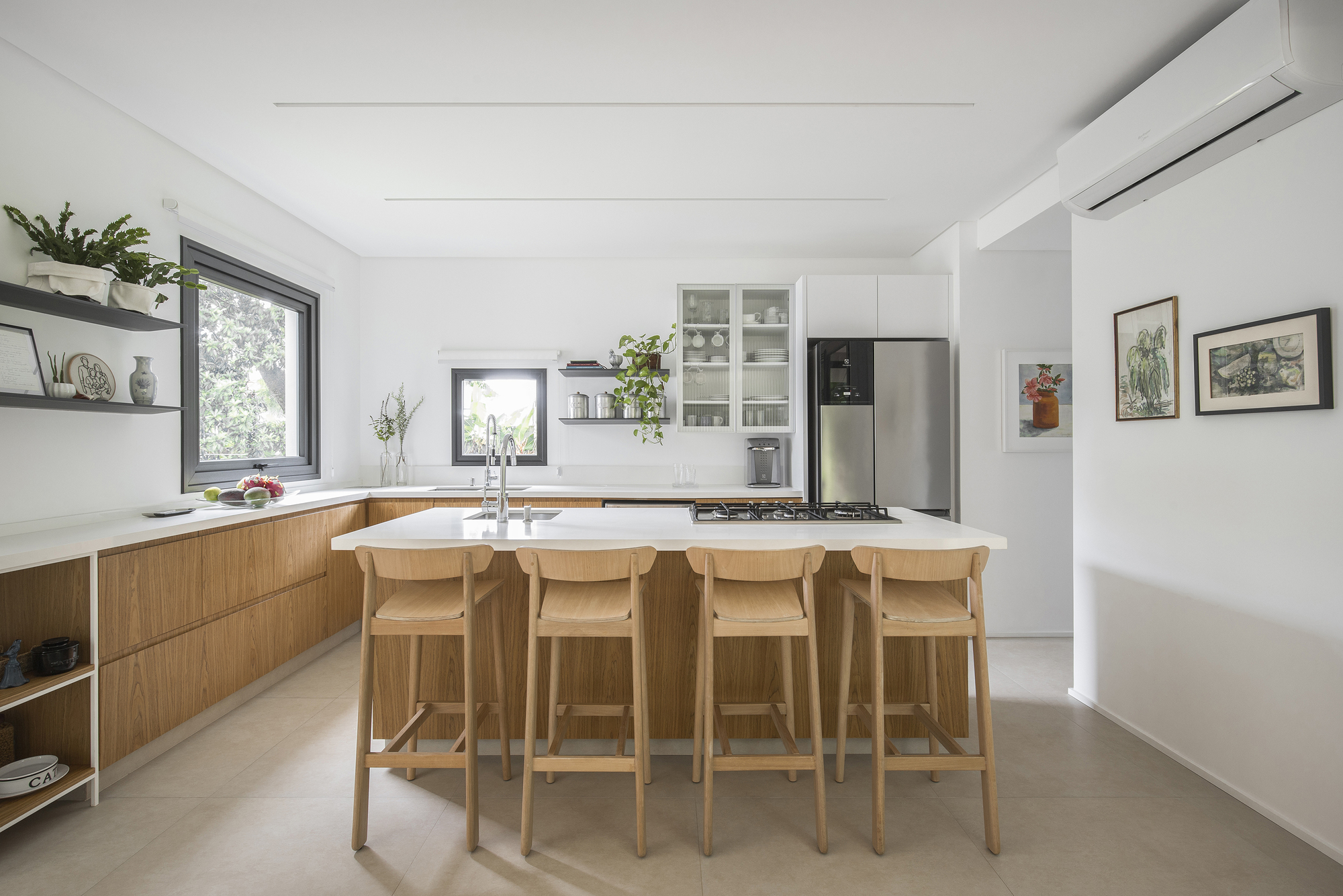Open kitchen with timber cabinetry, island with four bar stools, and white countertops