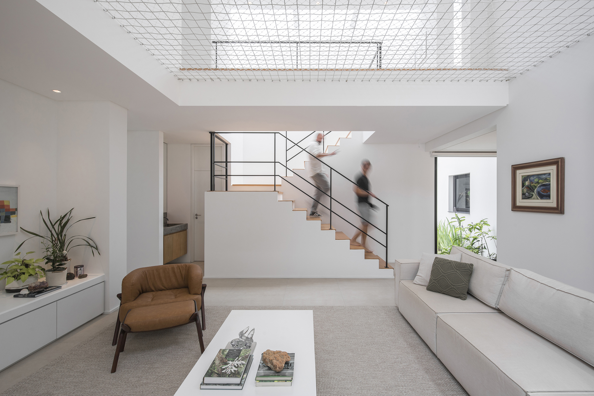 Interior view of white staircase with steel railings and wire mesh ceiling panel above