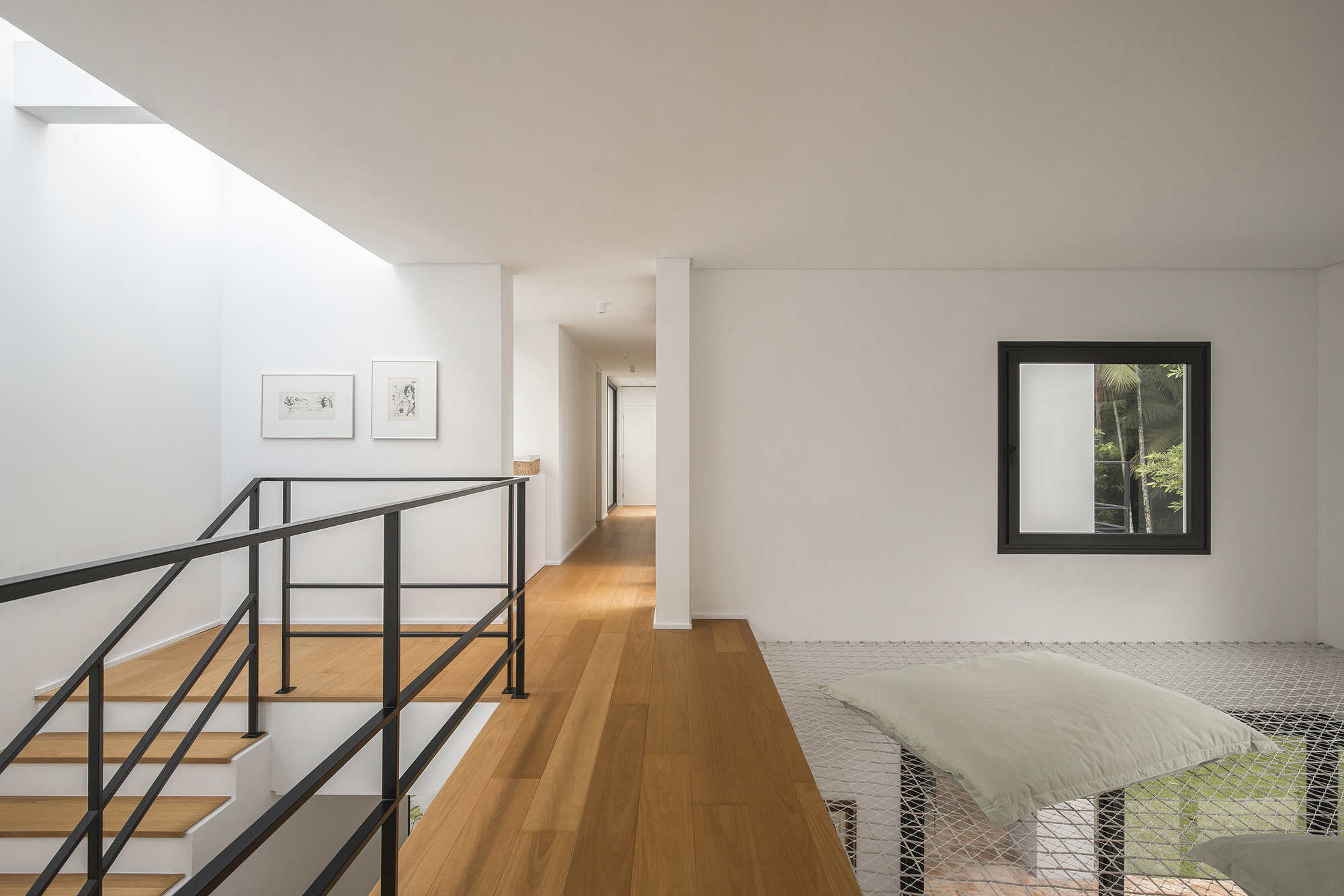 Upper corridor with timber flooring, steel railing overlooking mesh screen, and framed window