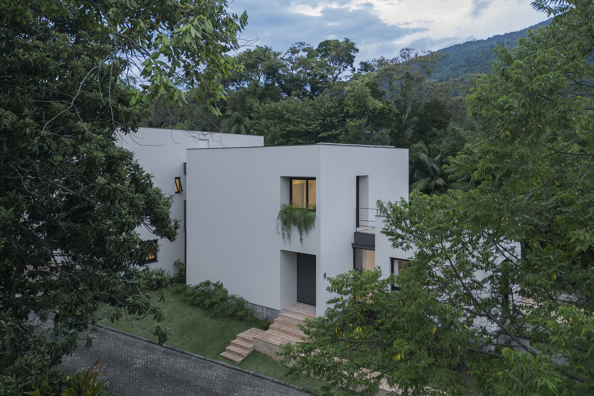 White stucco facade with timber entrance steps ascending the lawn under cloudy afternoon light