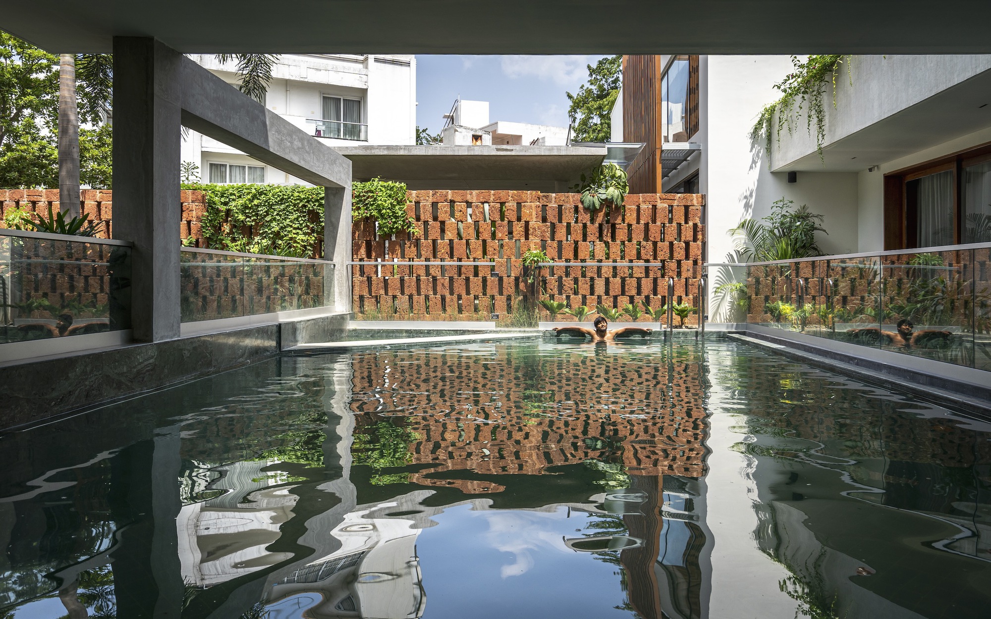 Reflecting pool bordered by brick screen walls and concrete beams framing interior rooms