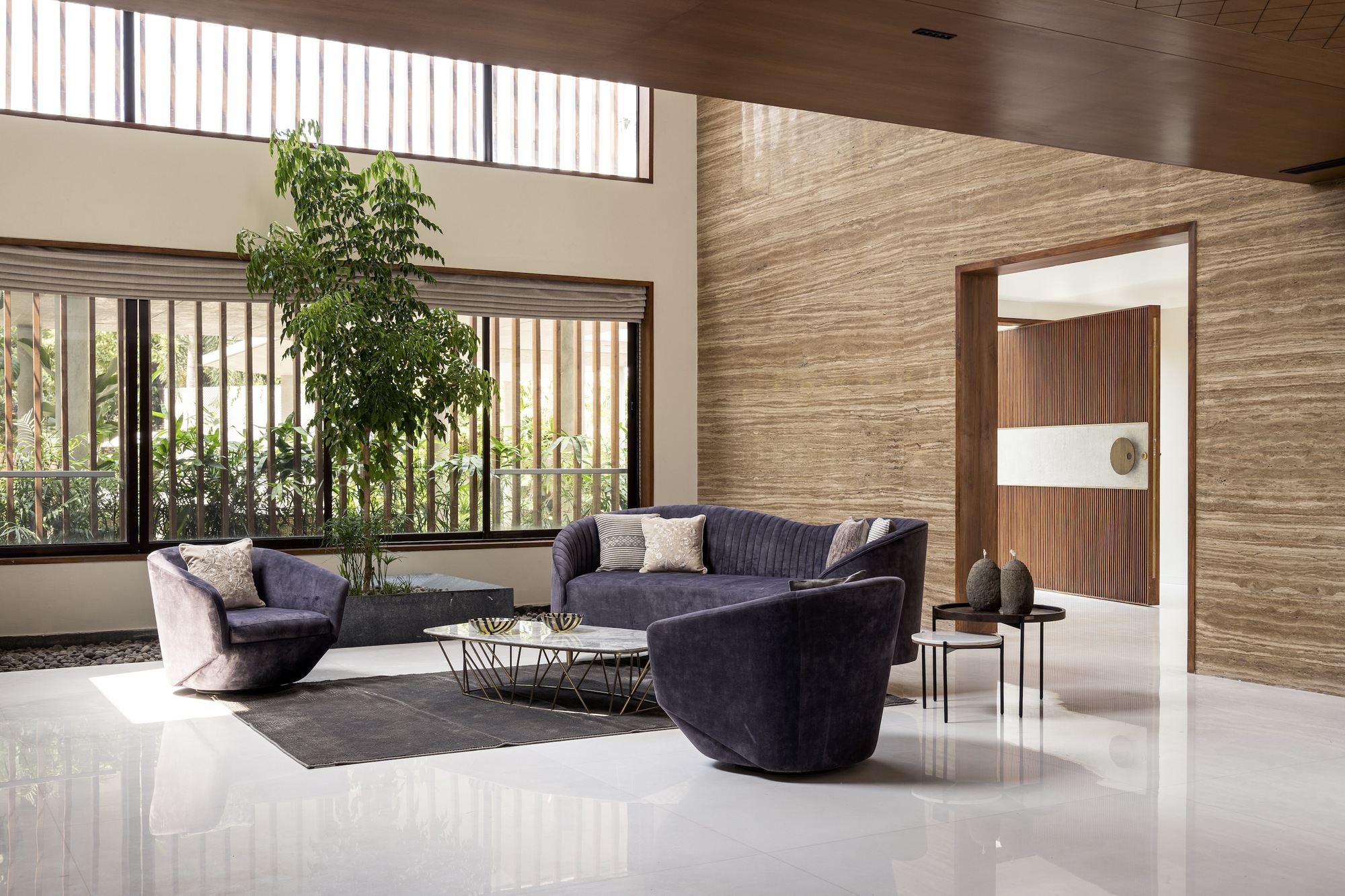 Living room with clerestory windows, horizontal stone wall cladding, and view to planted courtyard