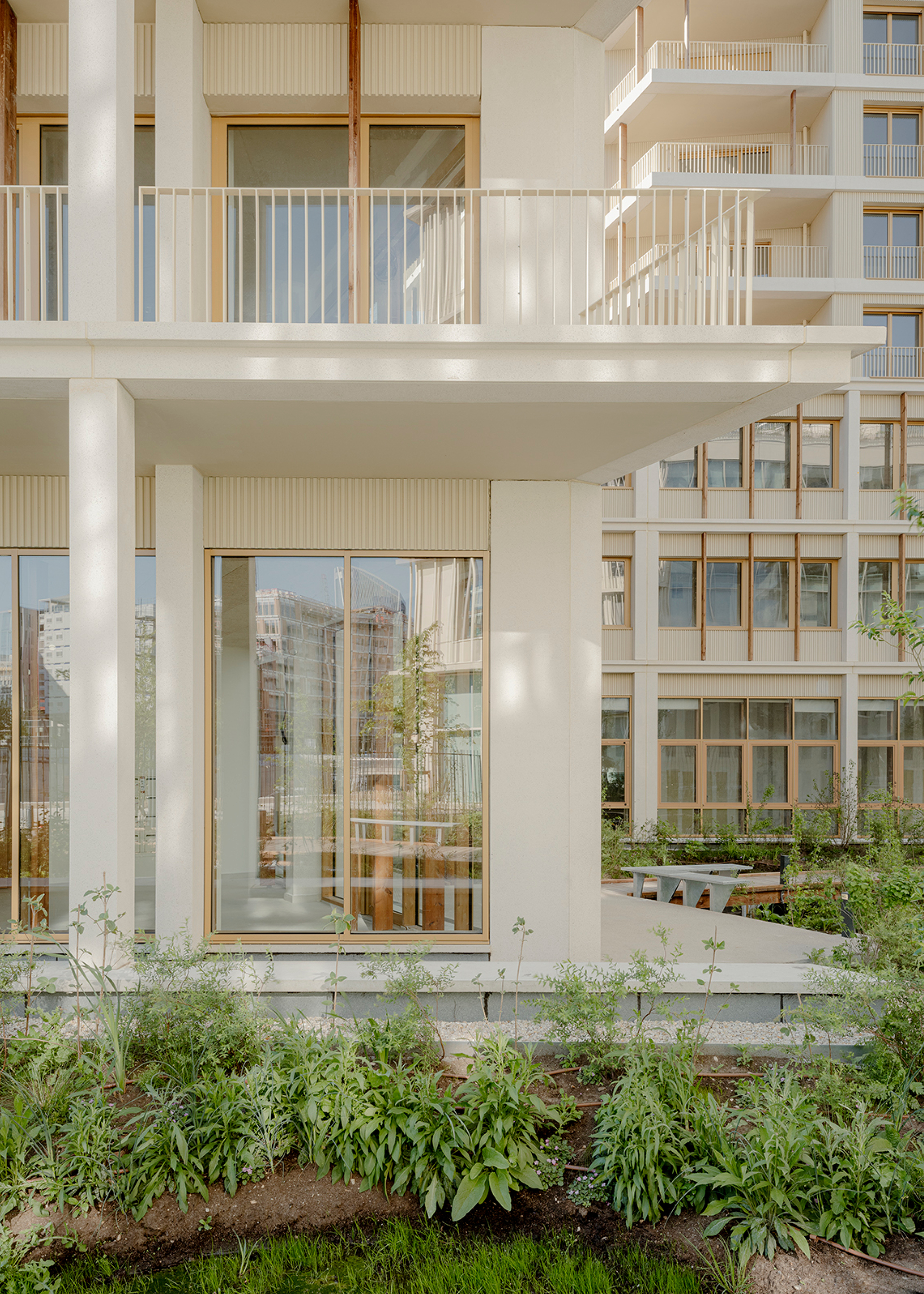 Ground floor unit with glazed doors opening to a planted garden bed in afternoon light
