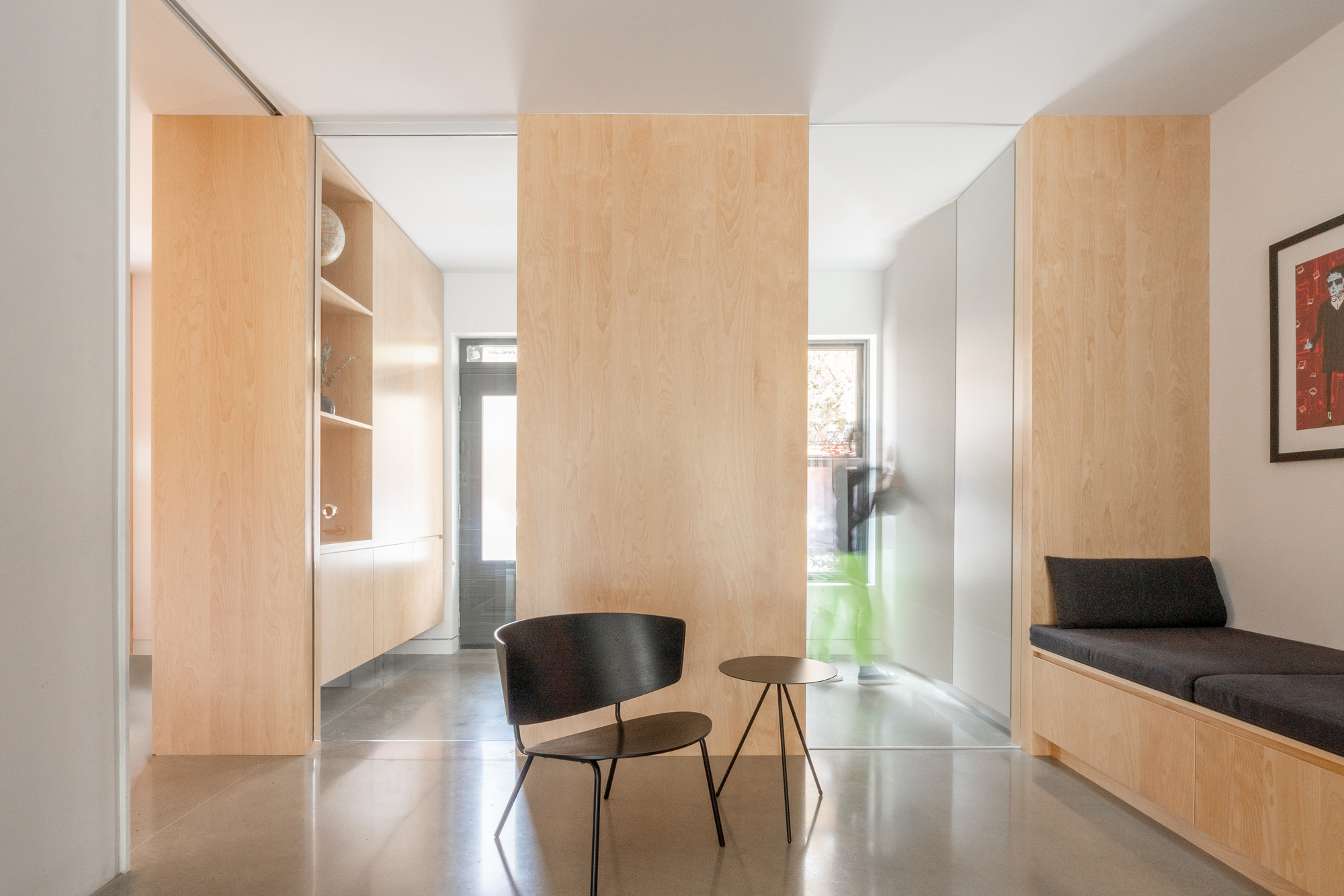 Hallway with pale wood partition panels, built-in bench seating, and polished concrete floor