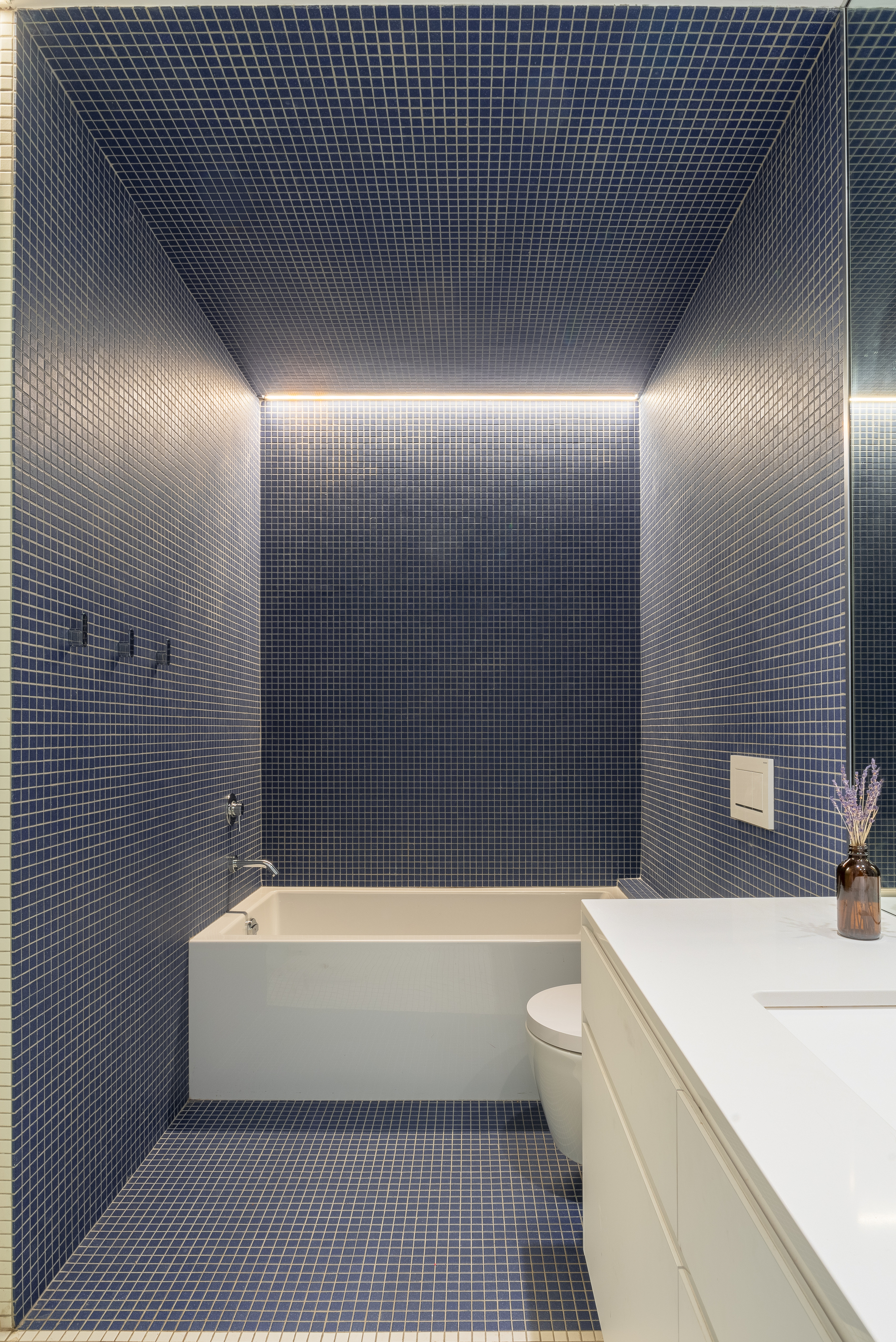 Bathroom with small blue mosaic tiles covering walls and ceiling, with concealed perimeter lighting