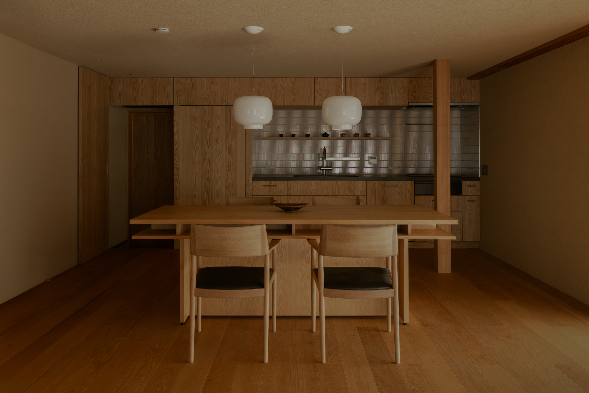 Dining area with timber table, chairs, and wood cabinetry beneath pendant lights