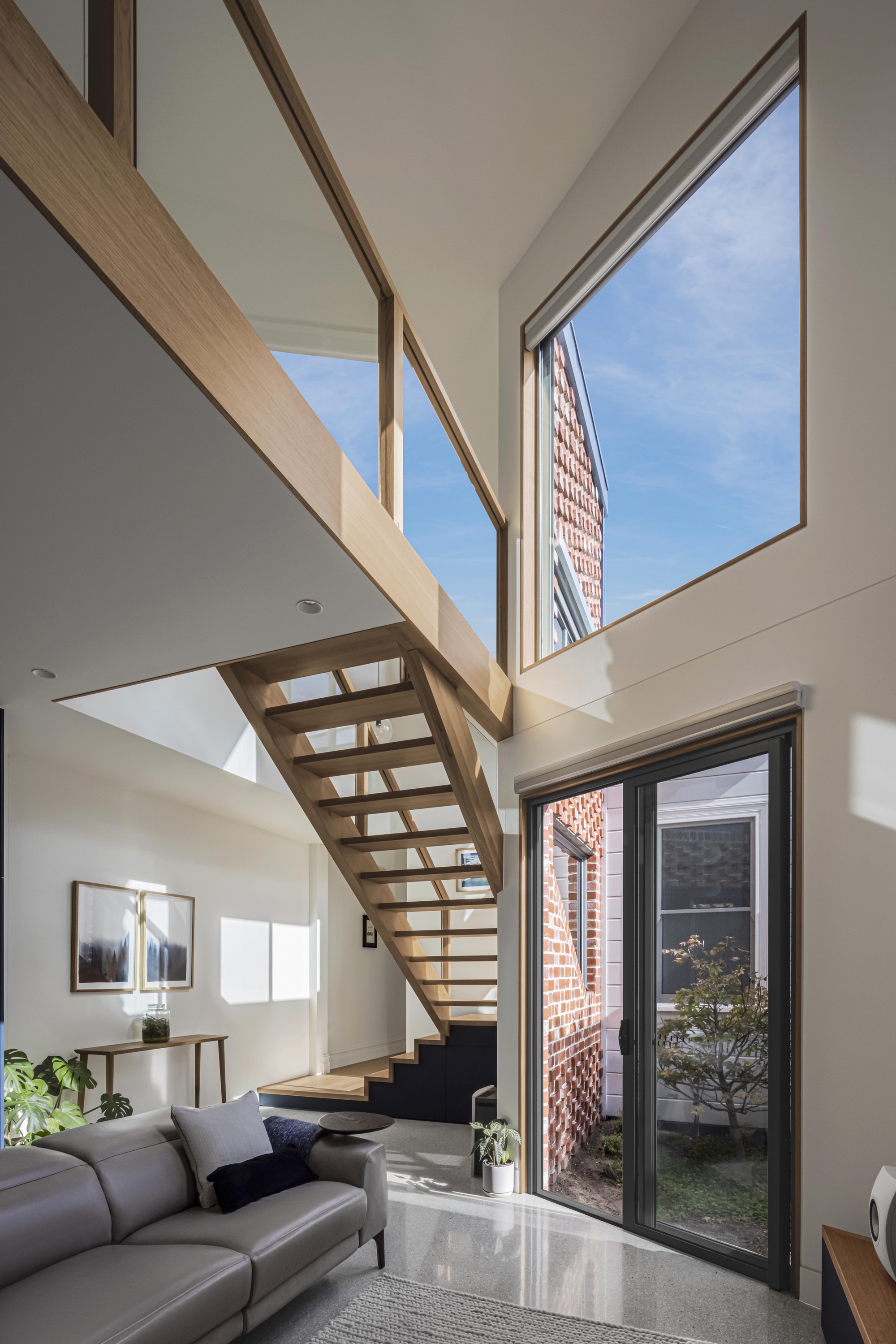 Double-height living space with timber open-tread staircase and glazed door to the internal courtyard