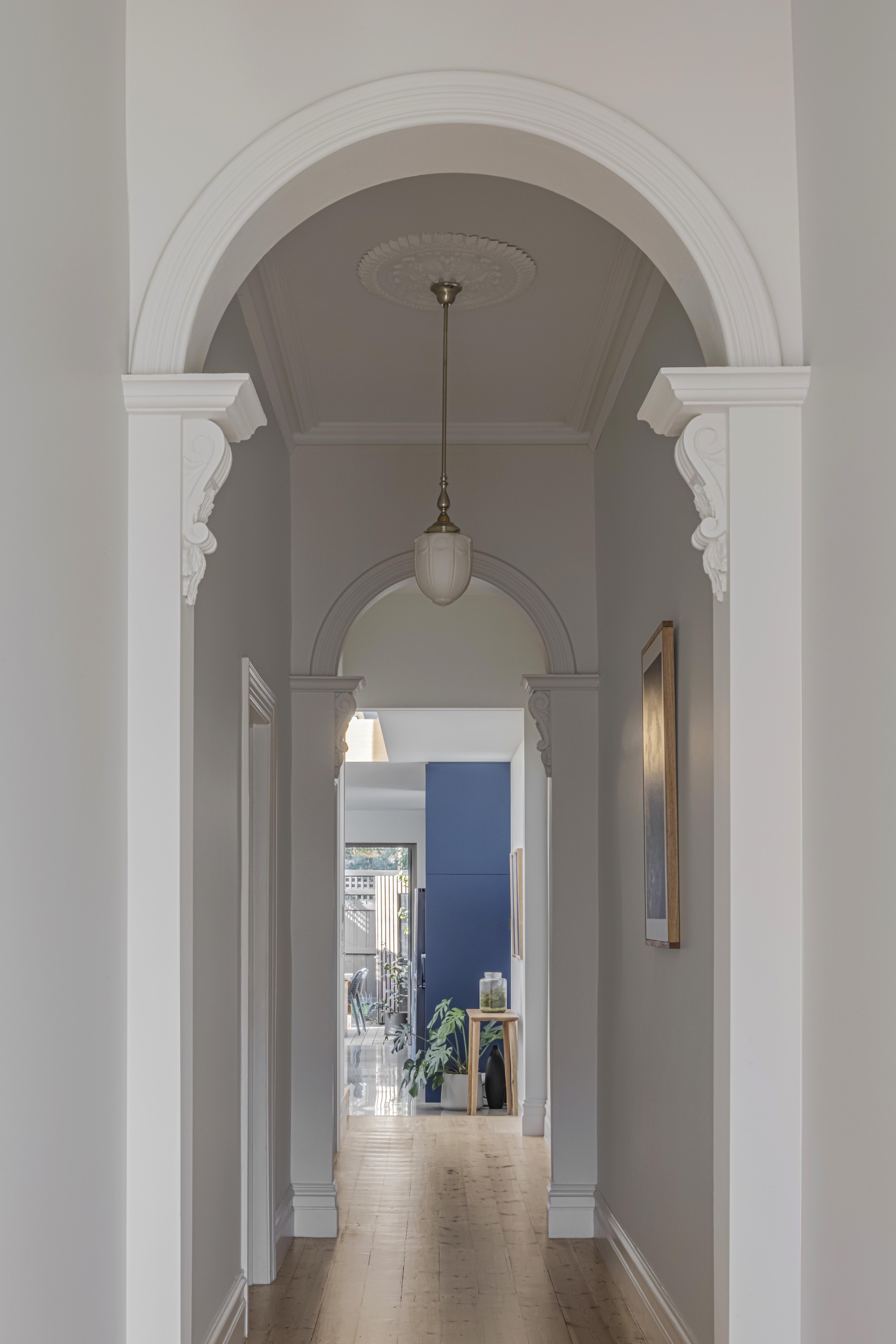 Enfilade of arched doorways with pendant light leading through the hallway to a blue room