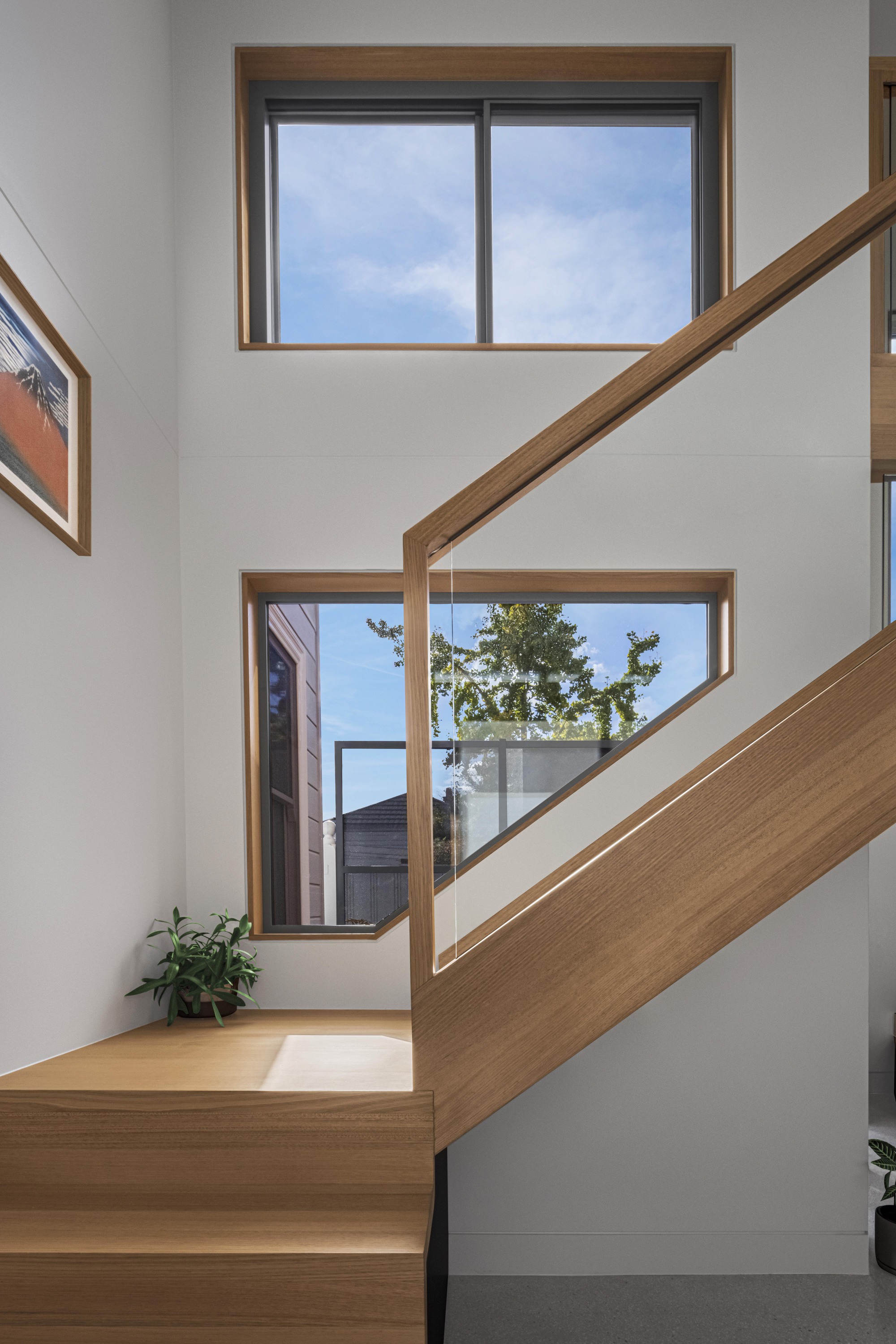 Staircase landing with timber-framed windows framing views of neighboring rooftops and trees