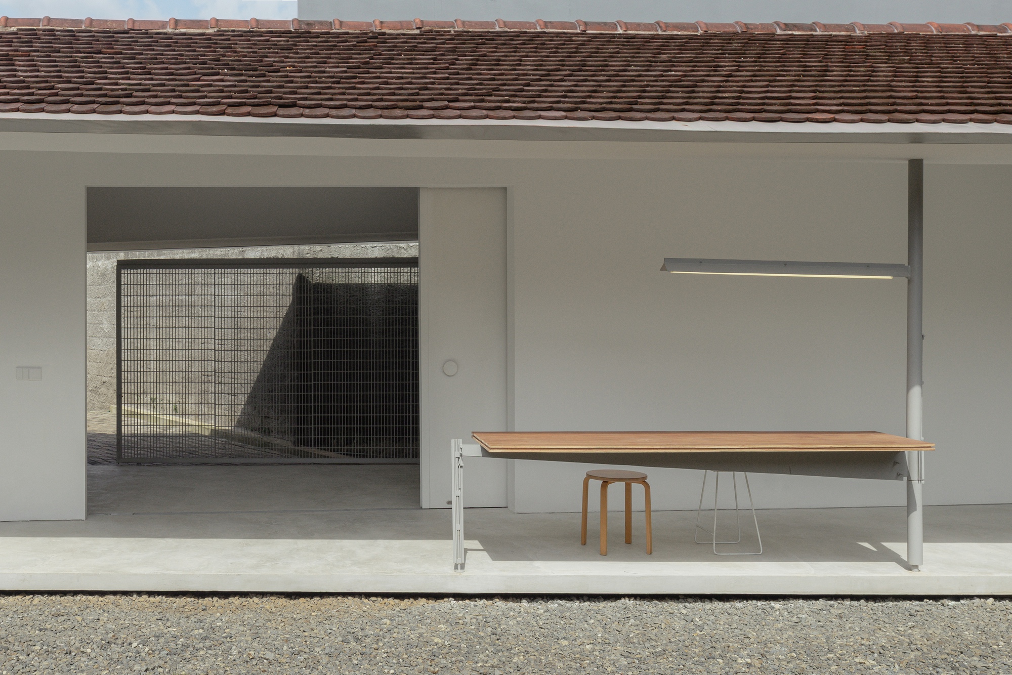 Covered terrace with a wooden bench and mesh screen opening beneath a tiled roof overhang