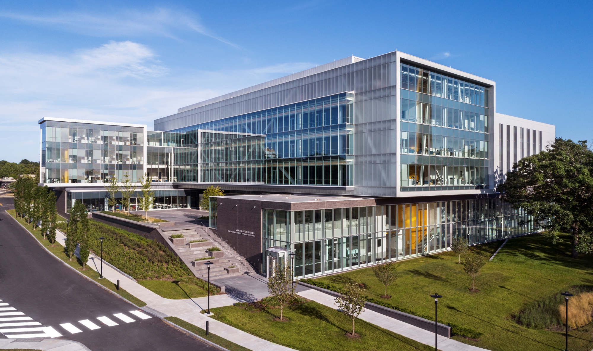 Elevated view of the translucent panel facade and glass curtain wall rising above landscaped lawn and approach road