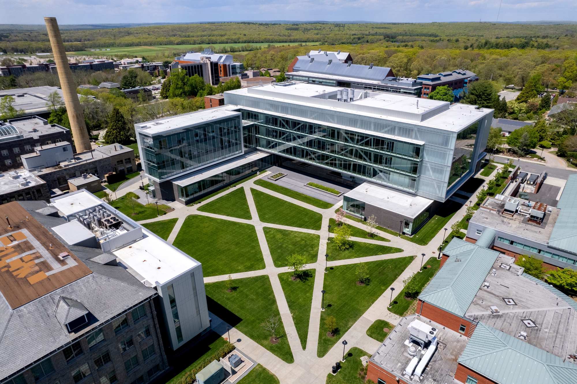 Aerial view of the glass and metal facade overlooking a geometric courtyard with diagonal lawn pathways