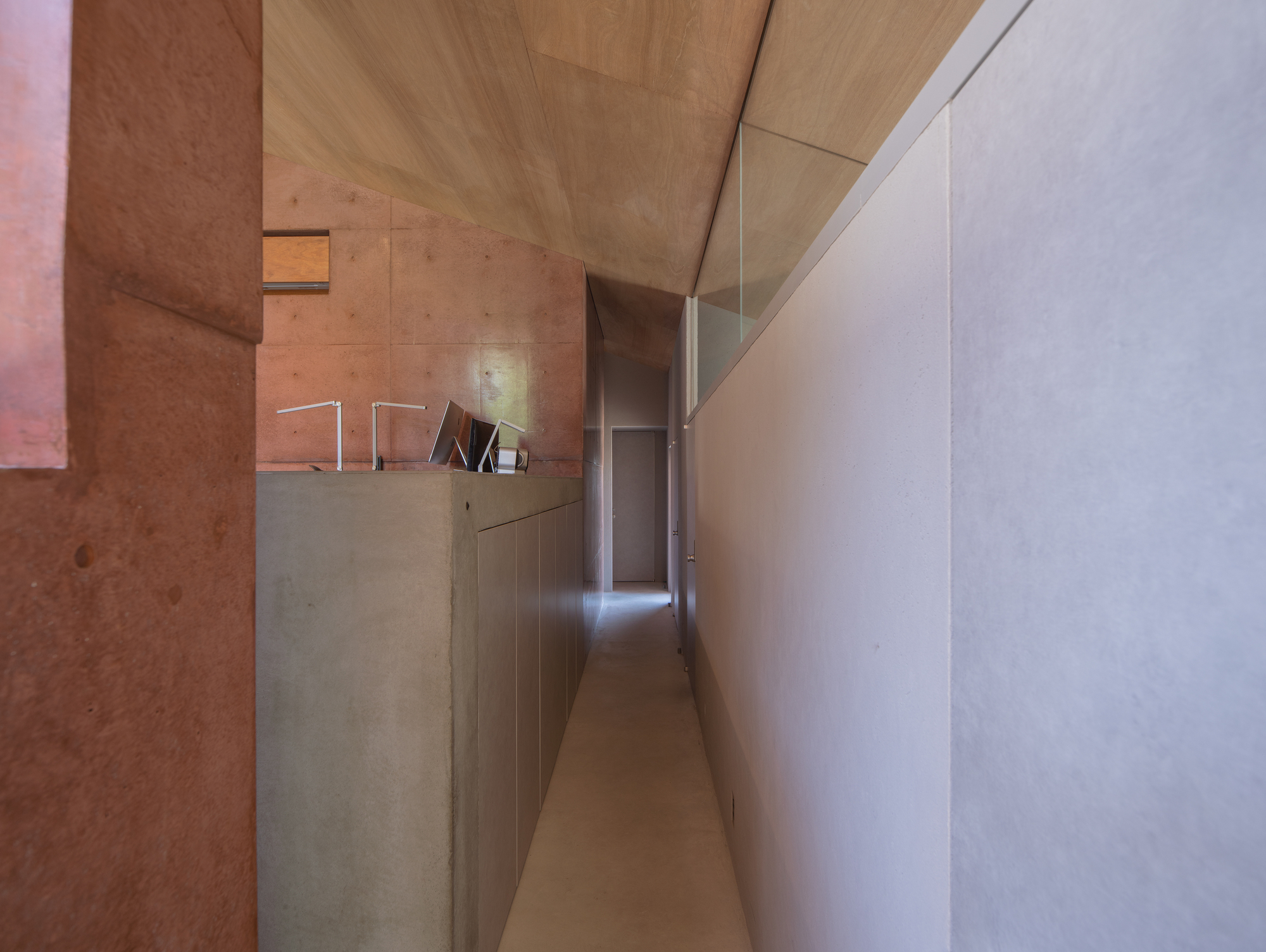 Corridor with timber ceiling, exposed concrete walls, and white millwork beneath a clerestory window