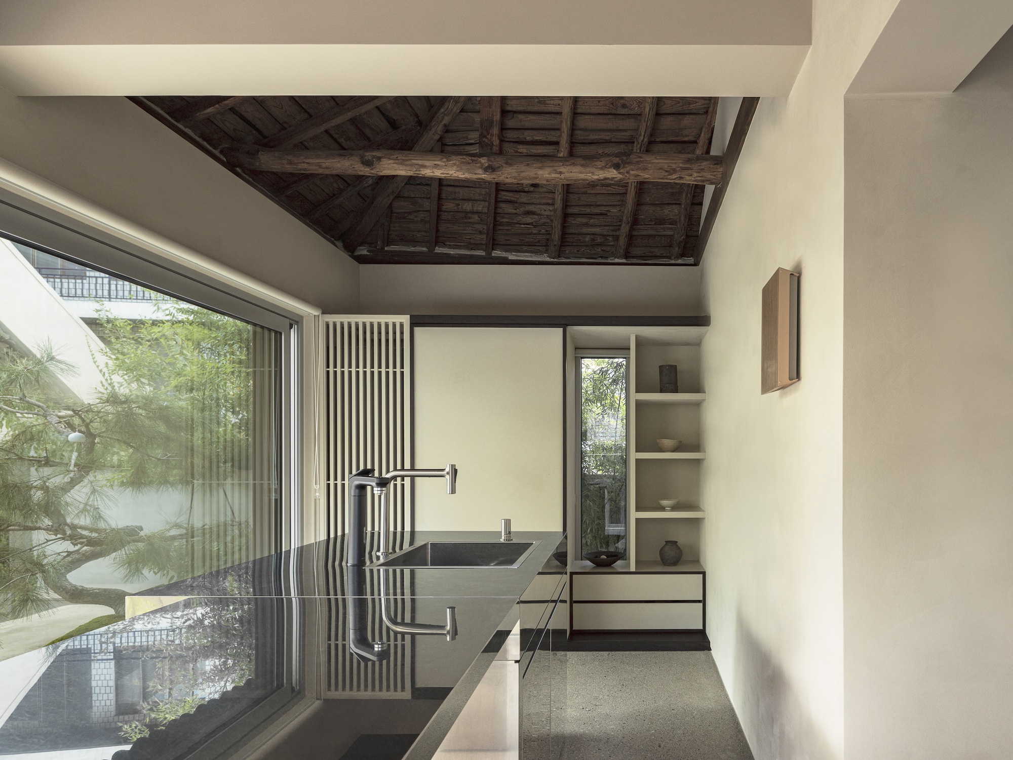 Bathroom with stone sink and vertical timber screen beneath reclaimed wooden ceiling beams