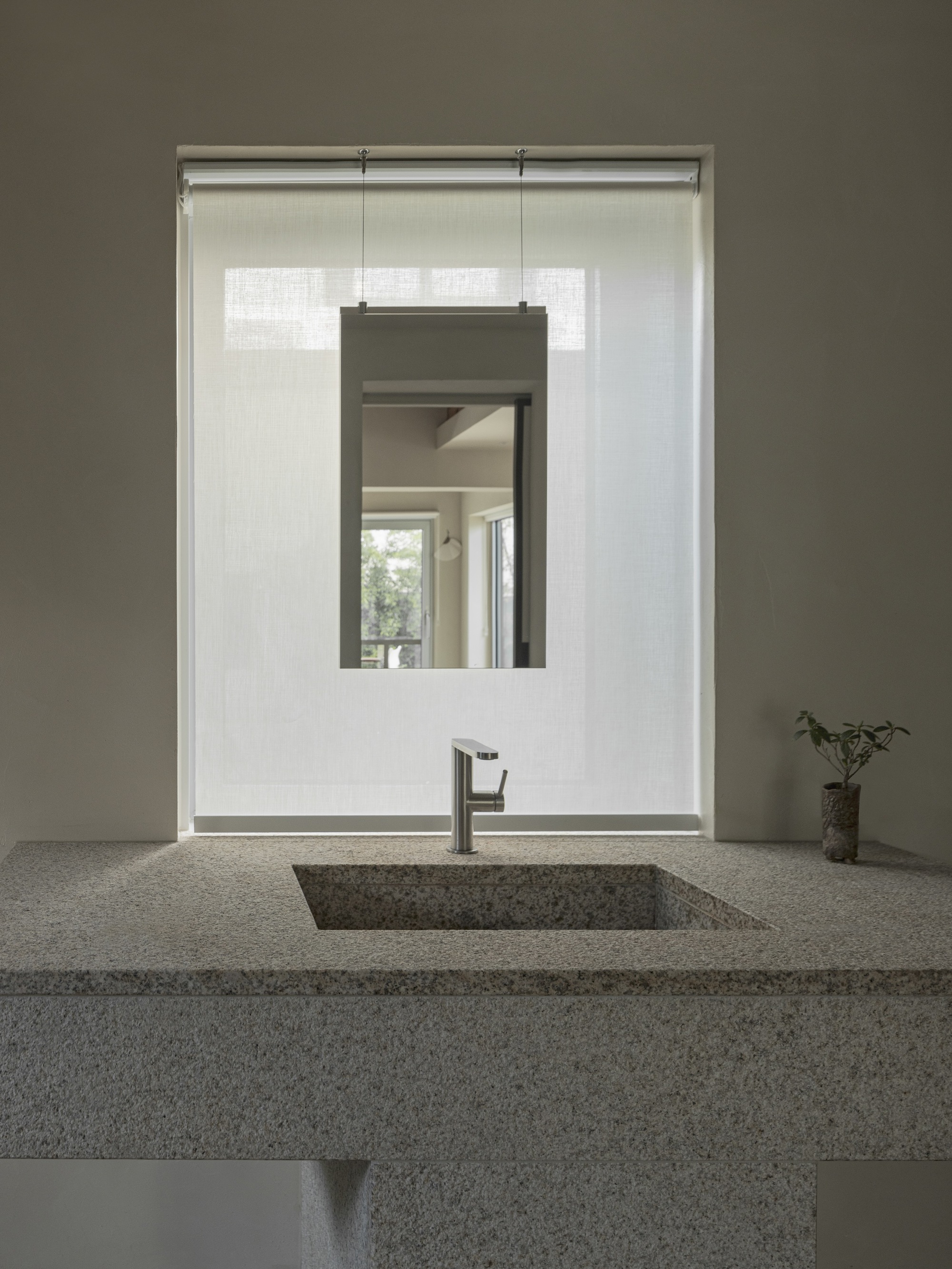 Terrazzo vanity counter with rectangular basin and suspended mirror framed by white tile