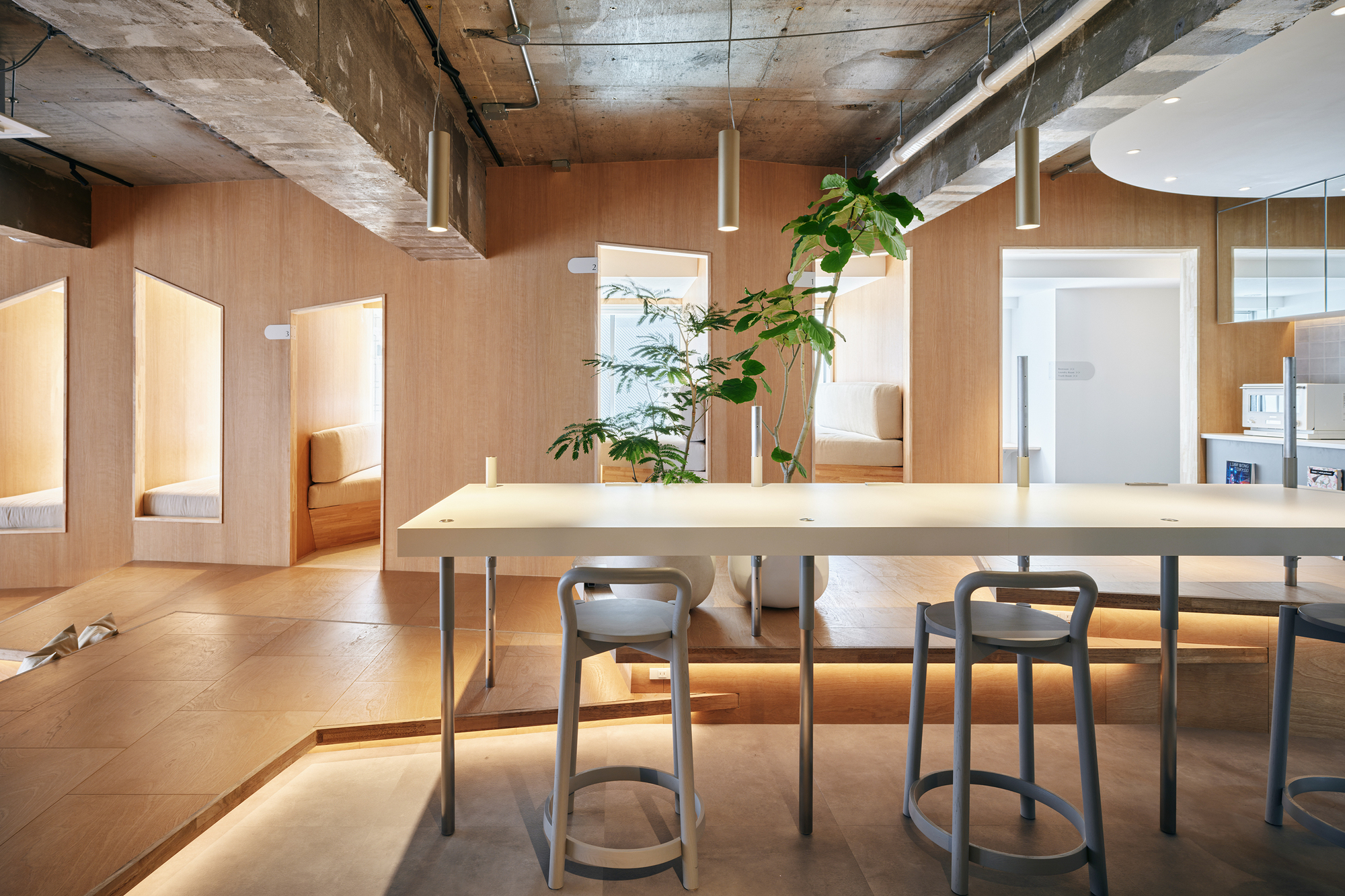 Plywood dining table with pendant lights and arched openings framing sleeping alcoves beyond