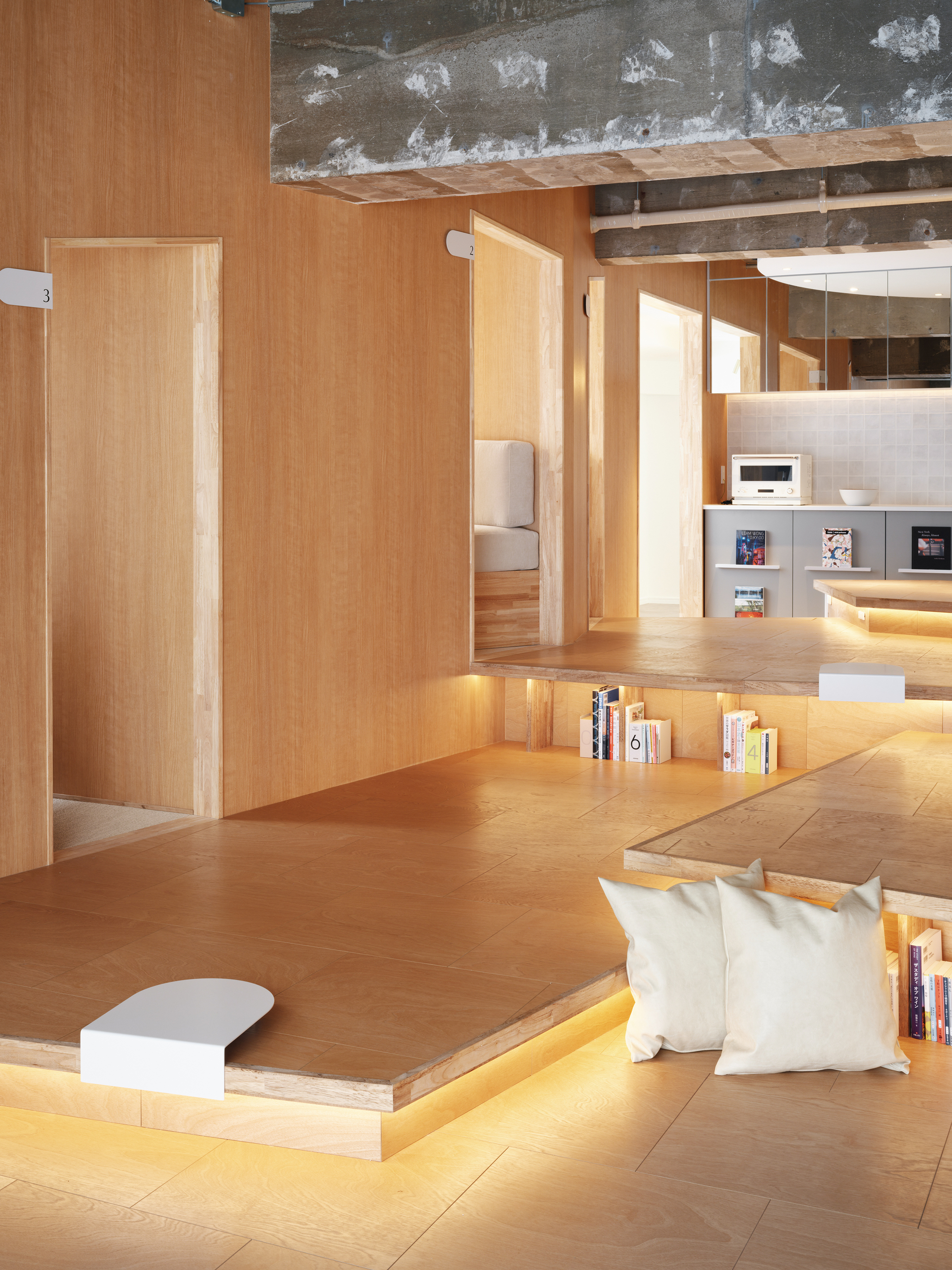 Sunken seating platform with integrated strip lighting and view through timber alcoves toward kitchen