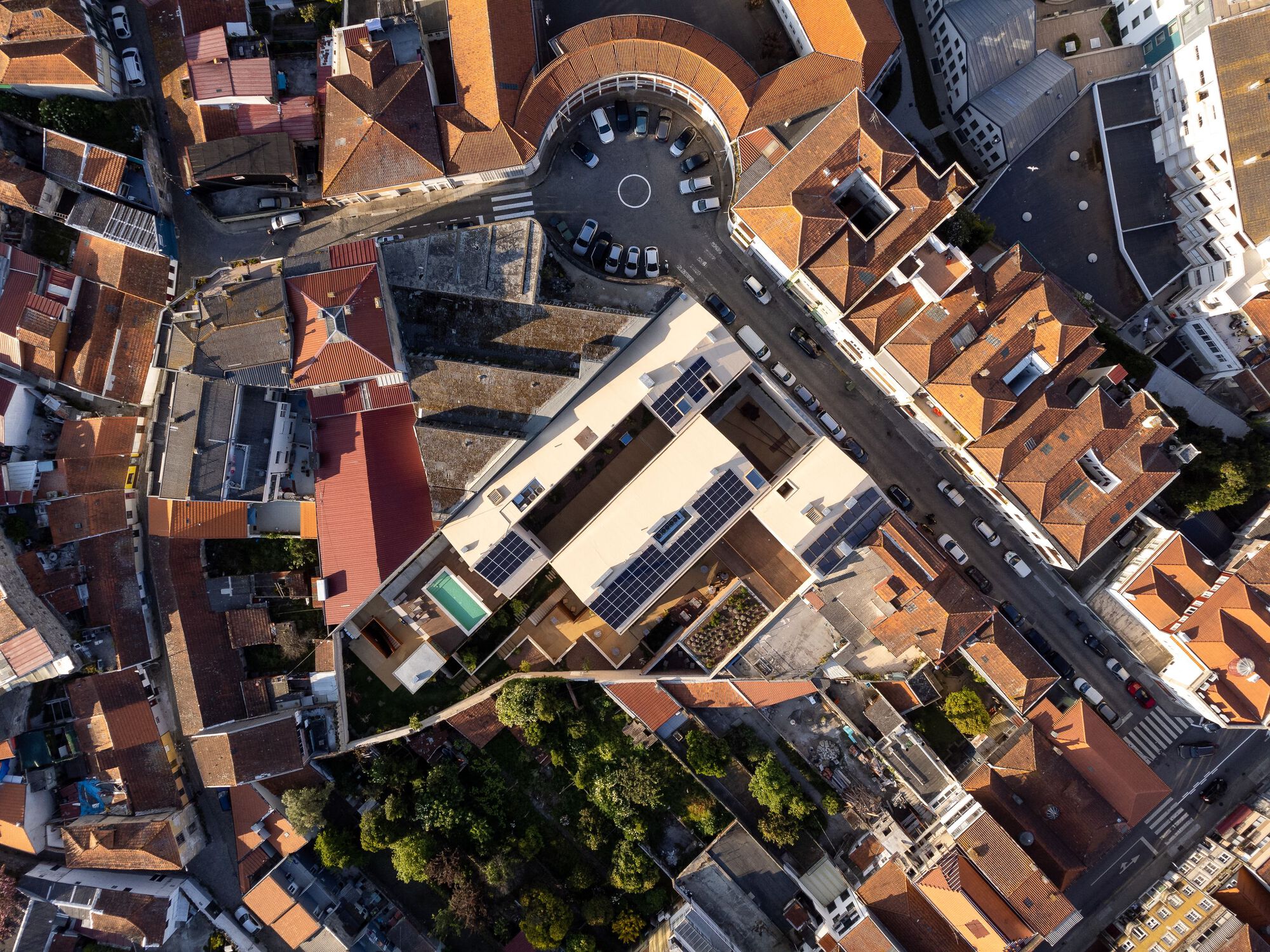 Aerial view of a rectangular courtyard with solar panels on the roof surrounded by terracotta tile roofs