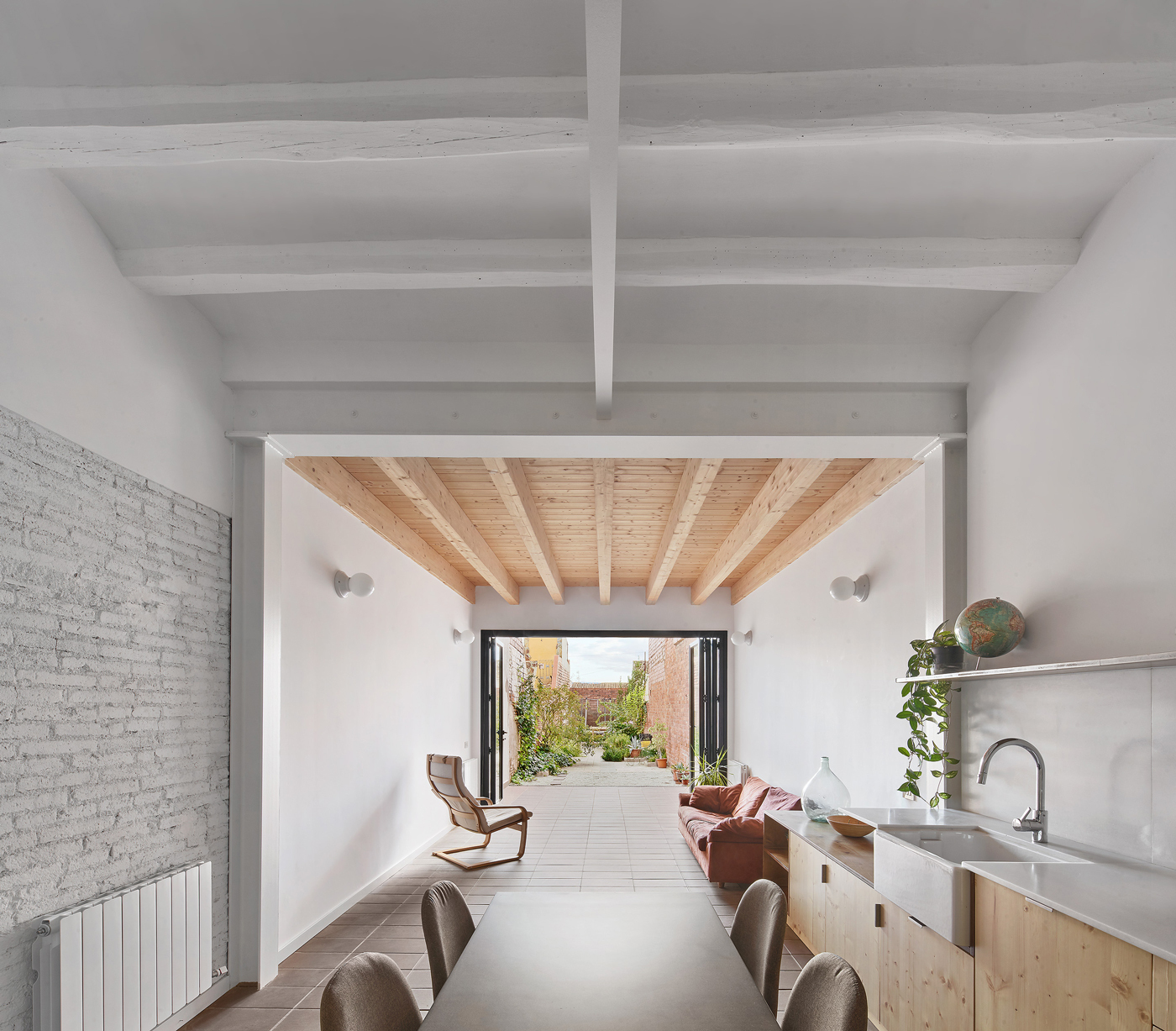 Interior view through dining and kitchen spaces toward the folding glass doors and planted courtyard beyond